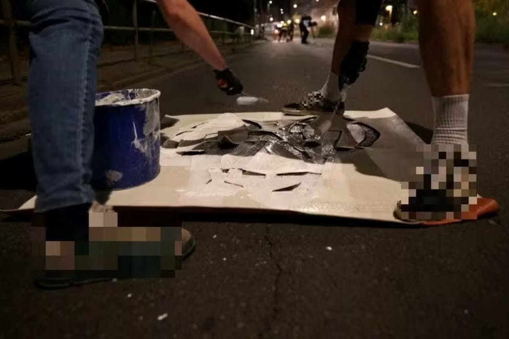 Die Klimaaktivisten malen den Pop-up-Radweg auf die Straße.