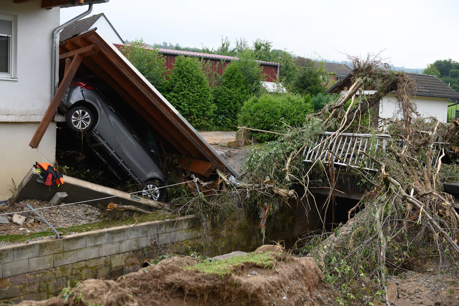 Ein zerstörtes Auto liegt unter einem abgerissenen Dach nach einem Unwetter im Trendelburger Stadtteil Gottsbüren. 