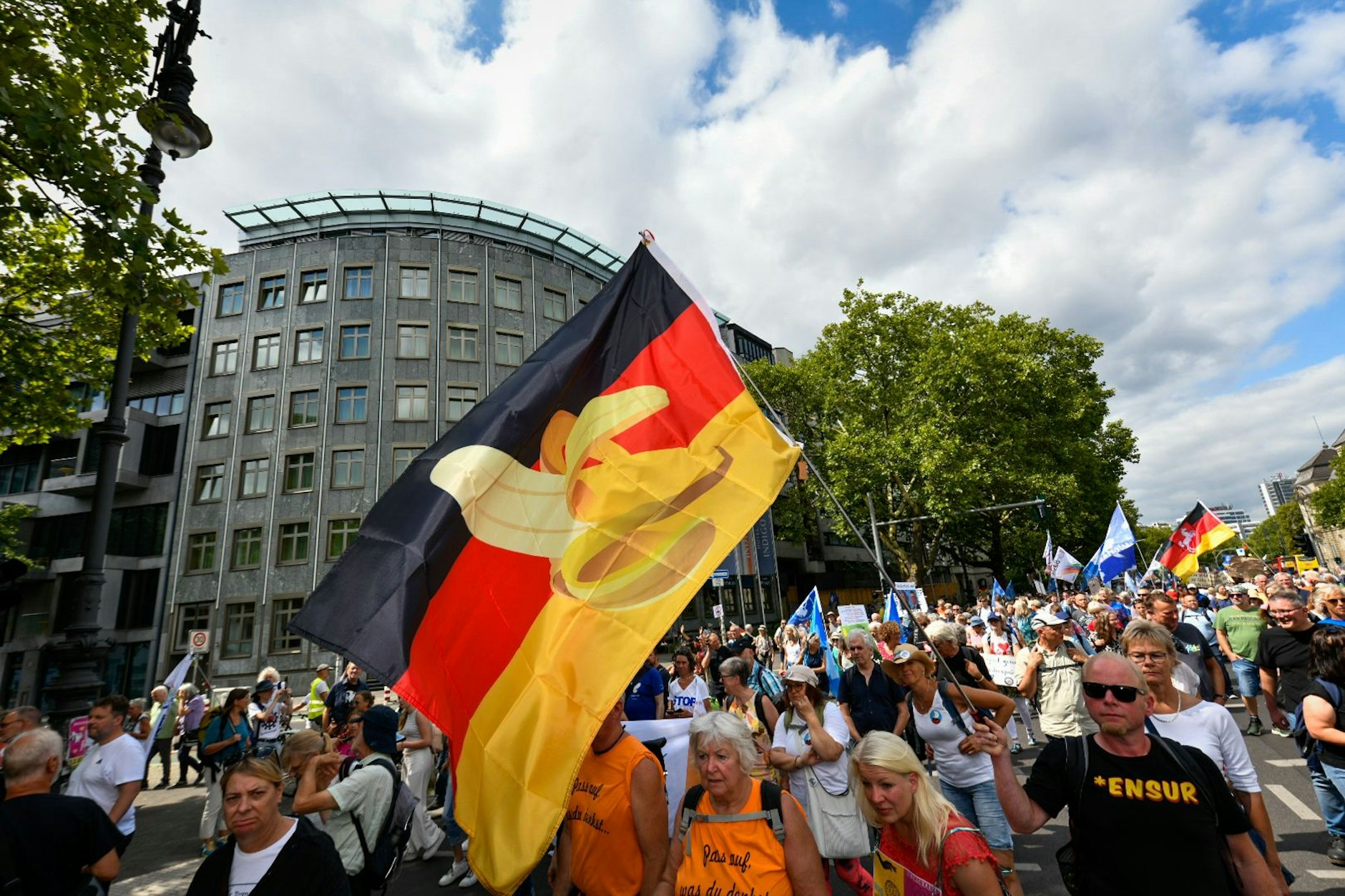Demonstranten schwenken eine Deutschlandfahne, auf der eine Banane abgebildet ist.