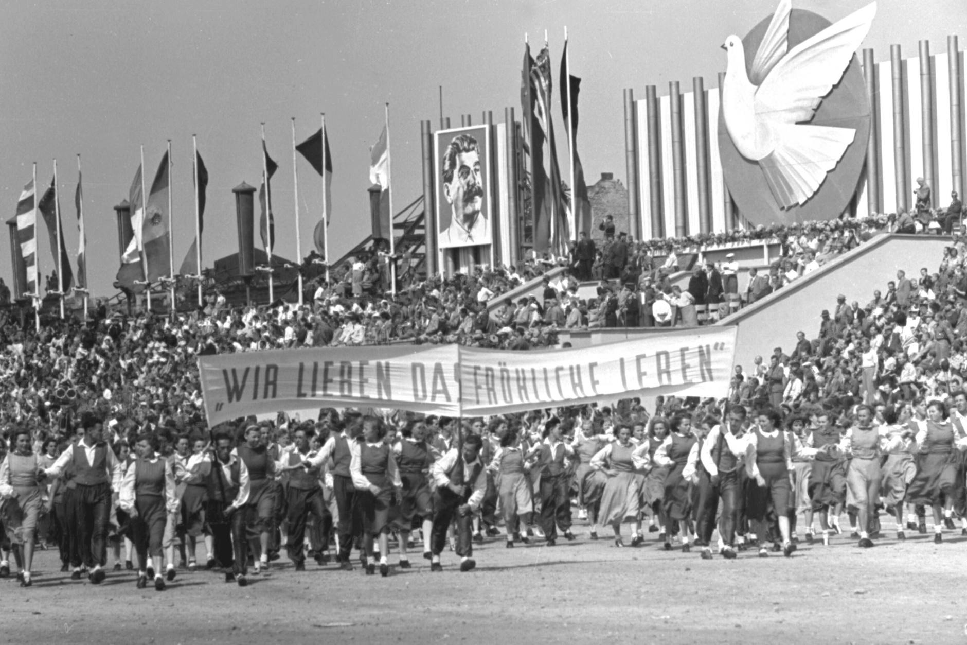 Eröffnungsfeier der III. Weltfestspiele in Berlin im Stadion der Weltjugend am 5. August 1951. Die Teilnehmer marschieren vorbei an einem Stalin-Porträt.
