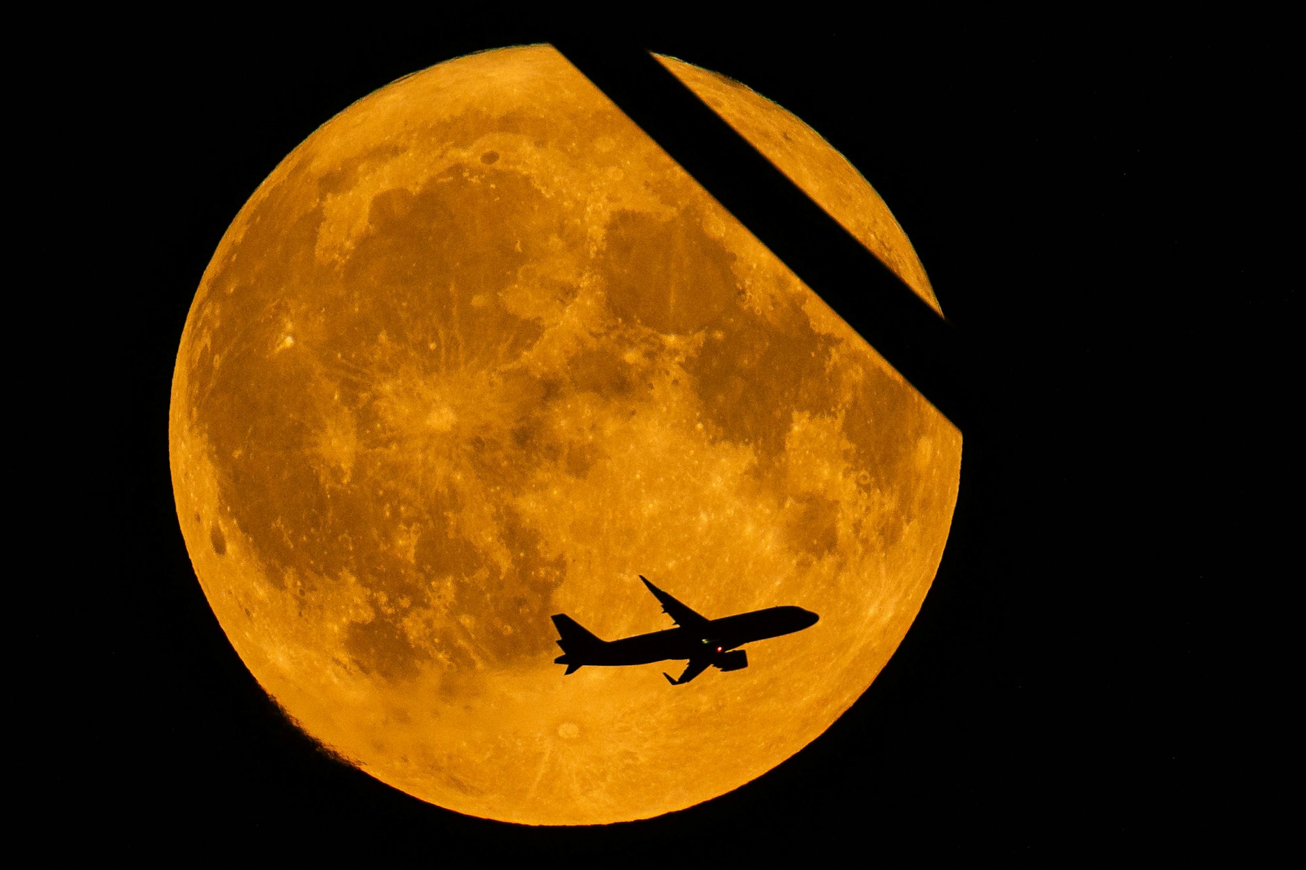 Der Supermond am 19. August 2024 in der Nähe von Stahnsdorf in Brandenburg.Ein vom Flughafen Berlin Brandenburg ( BER ) gestartetes Flugzeug und ein Flügel einer Windkraftanlage im Vordergrund. 