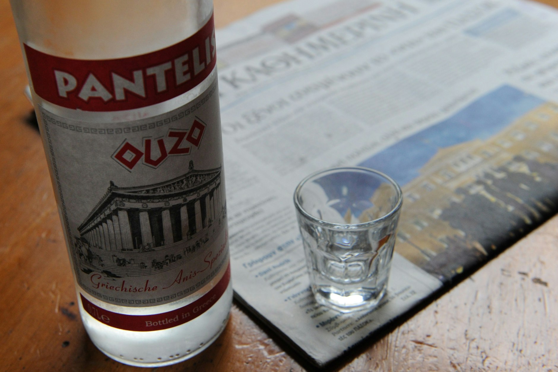 Eine Flasche Ouzo und ein Glas stehen auf einem Nachttisch.&nbsp;