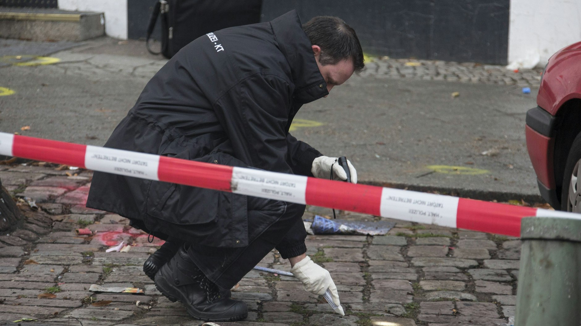 Nach einer Schießerei vor einem Club in Berlin-Reinickendorf sammelt ein Polizist Spuren am Tatort.