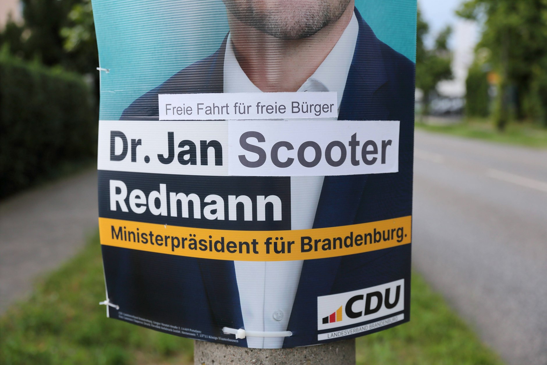 Witzbolde haben in Brandenburg Wahlplakate verfremdet. Aus Dr. Jan Redmann wurde Dr. Jan Scooter Redmann. Darüber steht Freie Fahrt für freie Bürger.