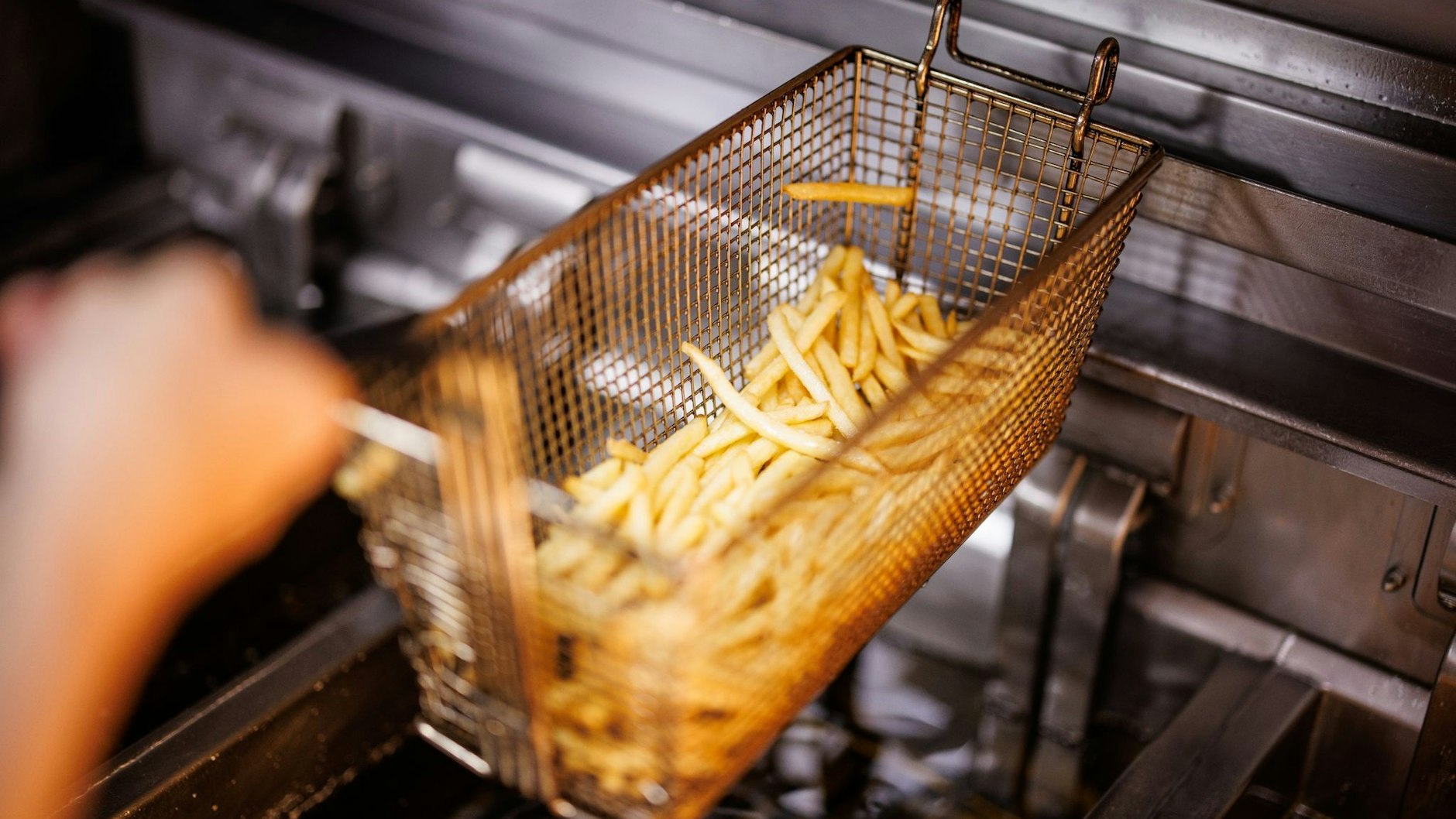 Eine Imbiss-Mitarbeiterin nimmt einen Korb mit Pommes Frites aus der Fritteuse. Mit den Ölresten sollen nun Busse der BVG betankt werden.&nbsp;