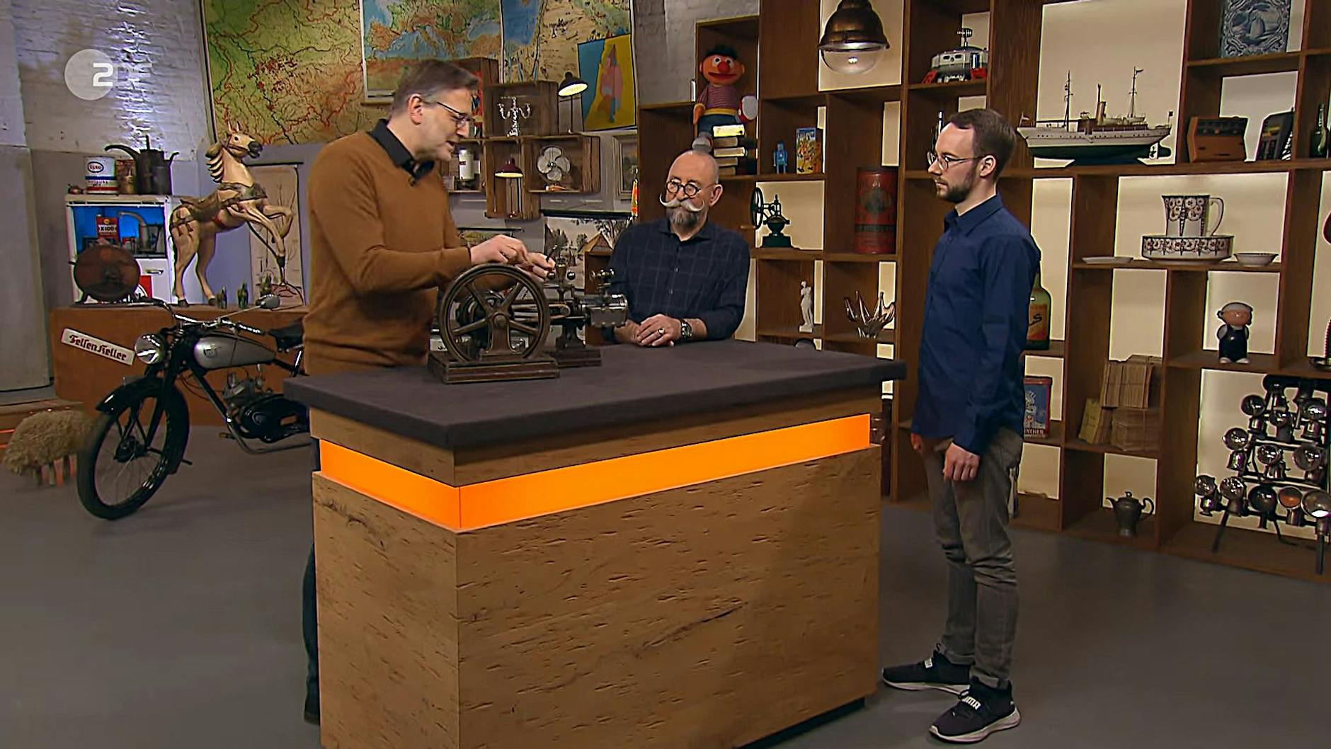 Student Daniel Hoff mit Moderator Horst Lichter und Experte Detlev Kümmel bei der Expertise bei Bares für Rares.