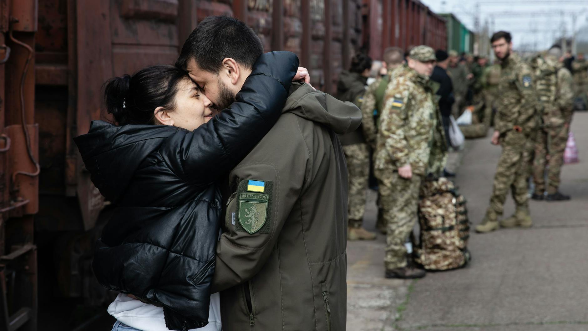 Ein Paar verabschiedet sich an einem Bahnhof. Der Mann dient in der ukrainischen Armee.