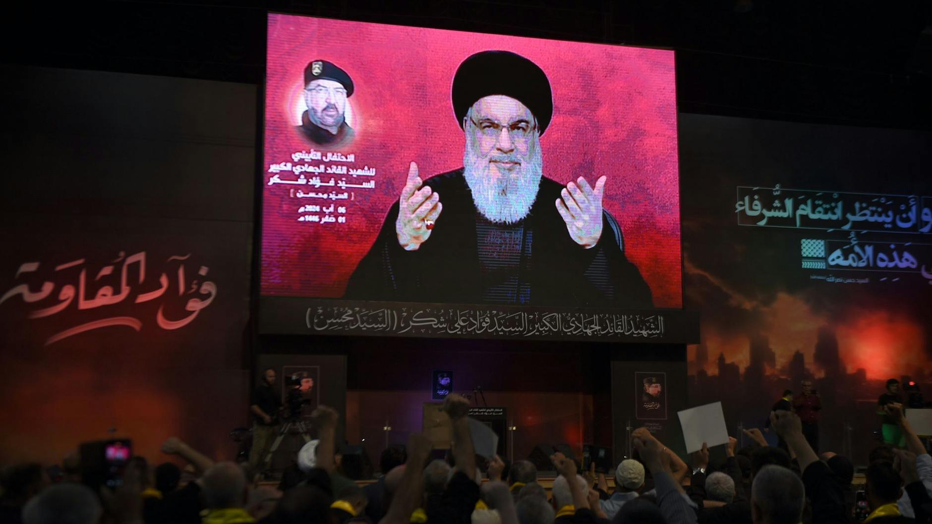 Anhänger erheben ihre Fäuste und jubeln, während sie eine Rede des Hisbollah-Führers Nasrallah auf einem Bildschirm verfolgen.
