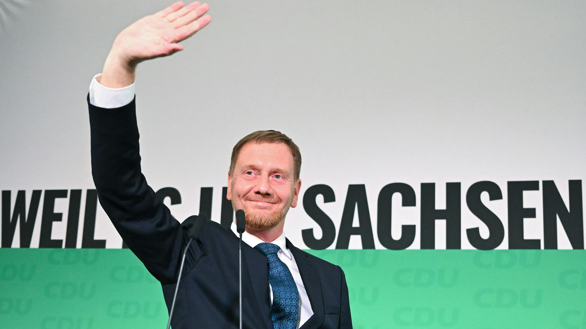 Michael Kretschmer (CDU), amtierender Ministerpräsident von Sachsen und Spitzenkandidat, winkt nach der Verkündung der ersten Hochrechnungen auf der Bühne. 