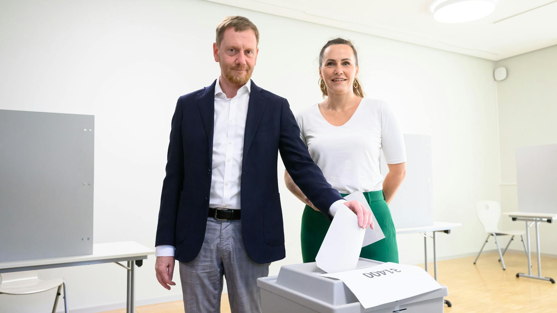 Michael Kretschmer (CDU), Ministerpräsident von Sachsen, steht mit seiner Frau Annett Hofmann bei der Stimmabgabe zur Landtagswahl in Sachsen im Wahllokal an einer Wahlurne.