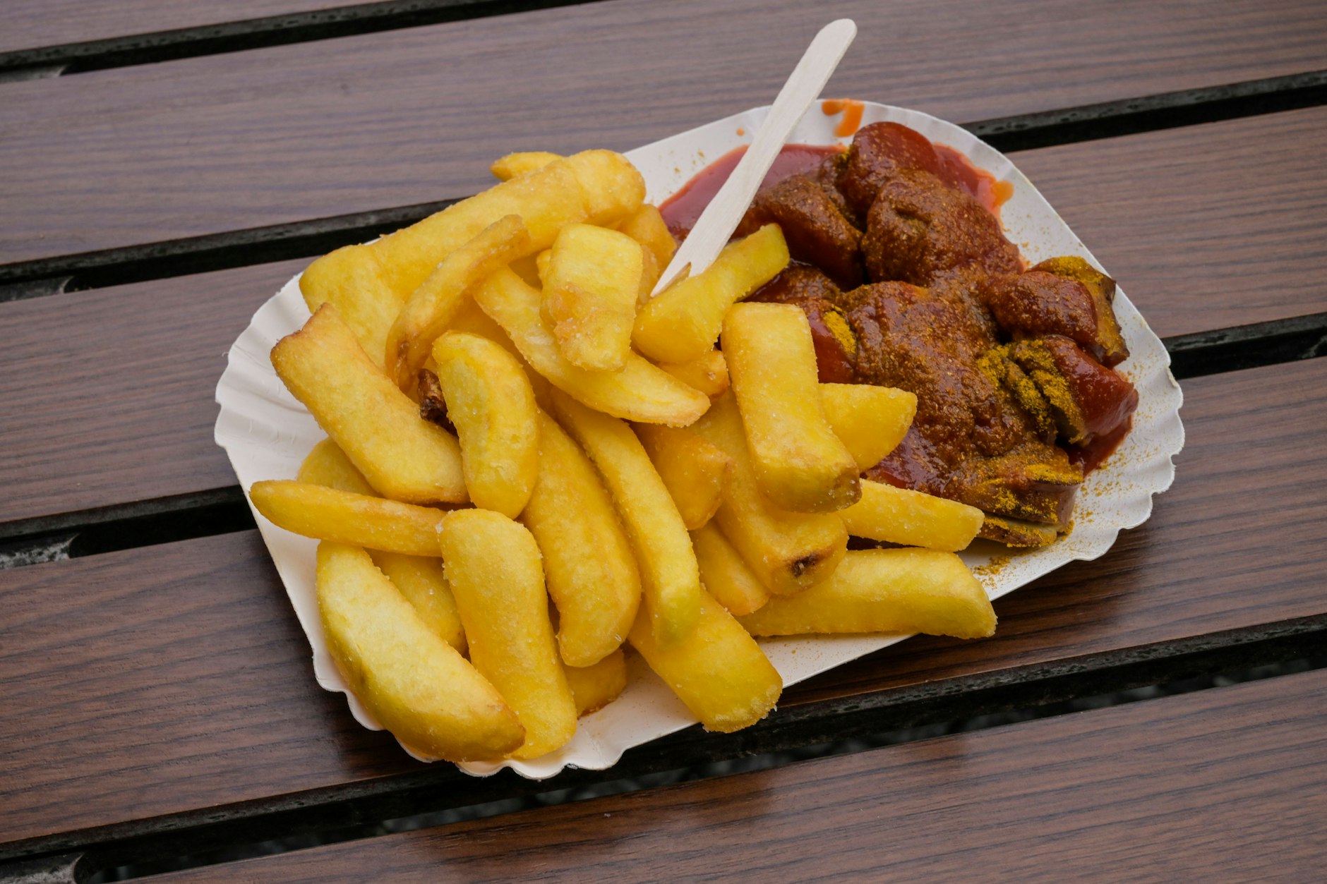 Zuhause zubereitete Currywurst mit hausgemachter Currysauce, knusprigen Pommes und einer Prise Currypulver – das perfekte Berliner Imbiss-Feeling für den heimischen Küchentisch!