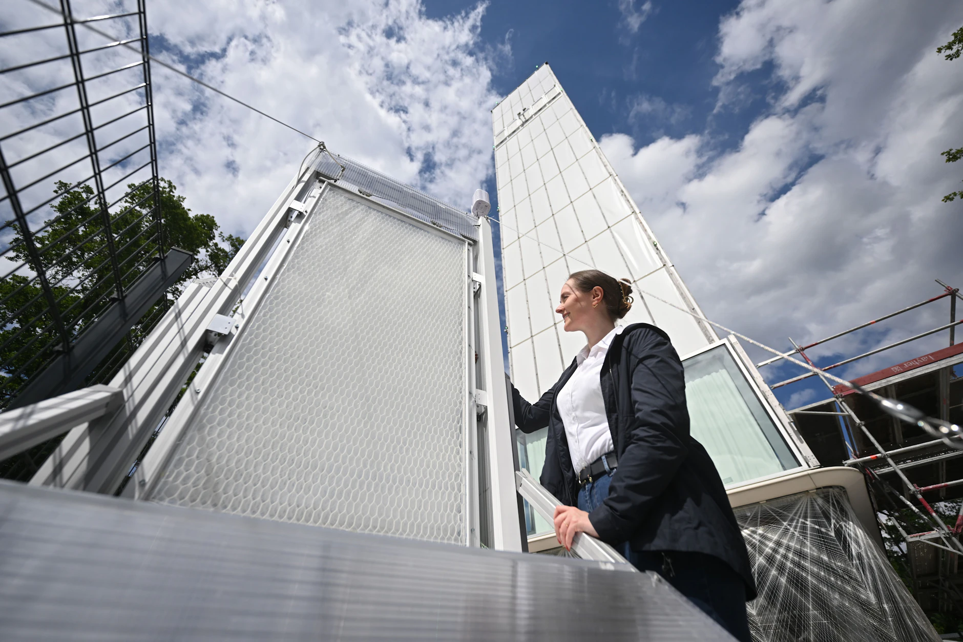 Christina Eisenbarth, Gründerin von Hydroskin, zeigt an der Universität Stuttgart ein Hydroskin-Muster. Im Hintergrund steht das Experimental-Hochhaus, an dem die Wasserhaut getestet wird.