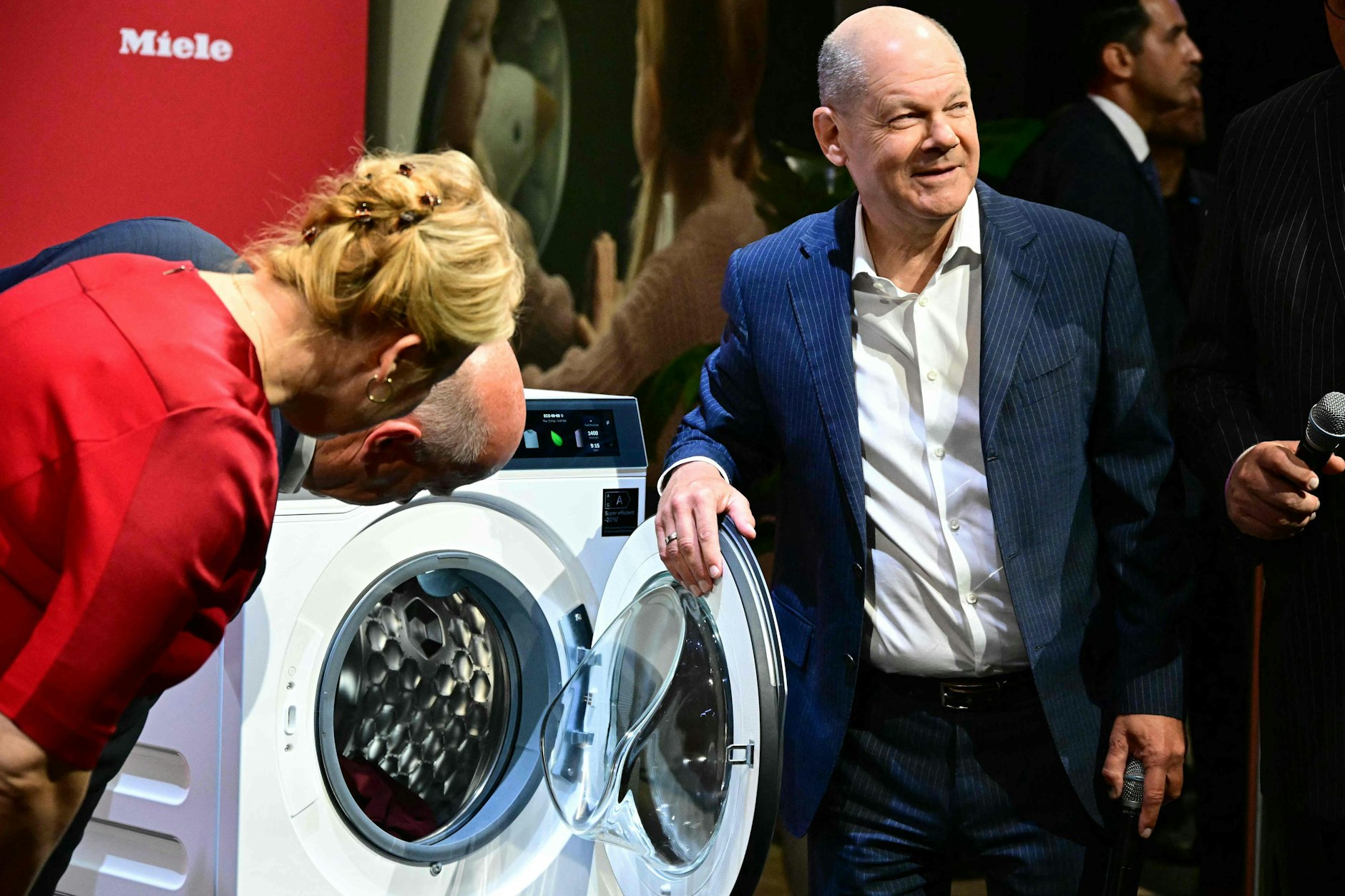 Der Bundeskanzler Olaf Scholz wird auf der IFA zum Bundeswäschemeister: Berlins Regierender Kai Wegner (CDU) und Wirtschaftssenatorin Franziska Giffey (SPD) schauen staunend zu. 