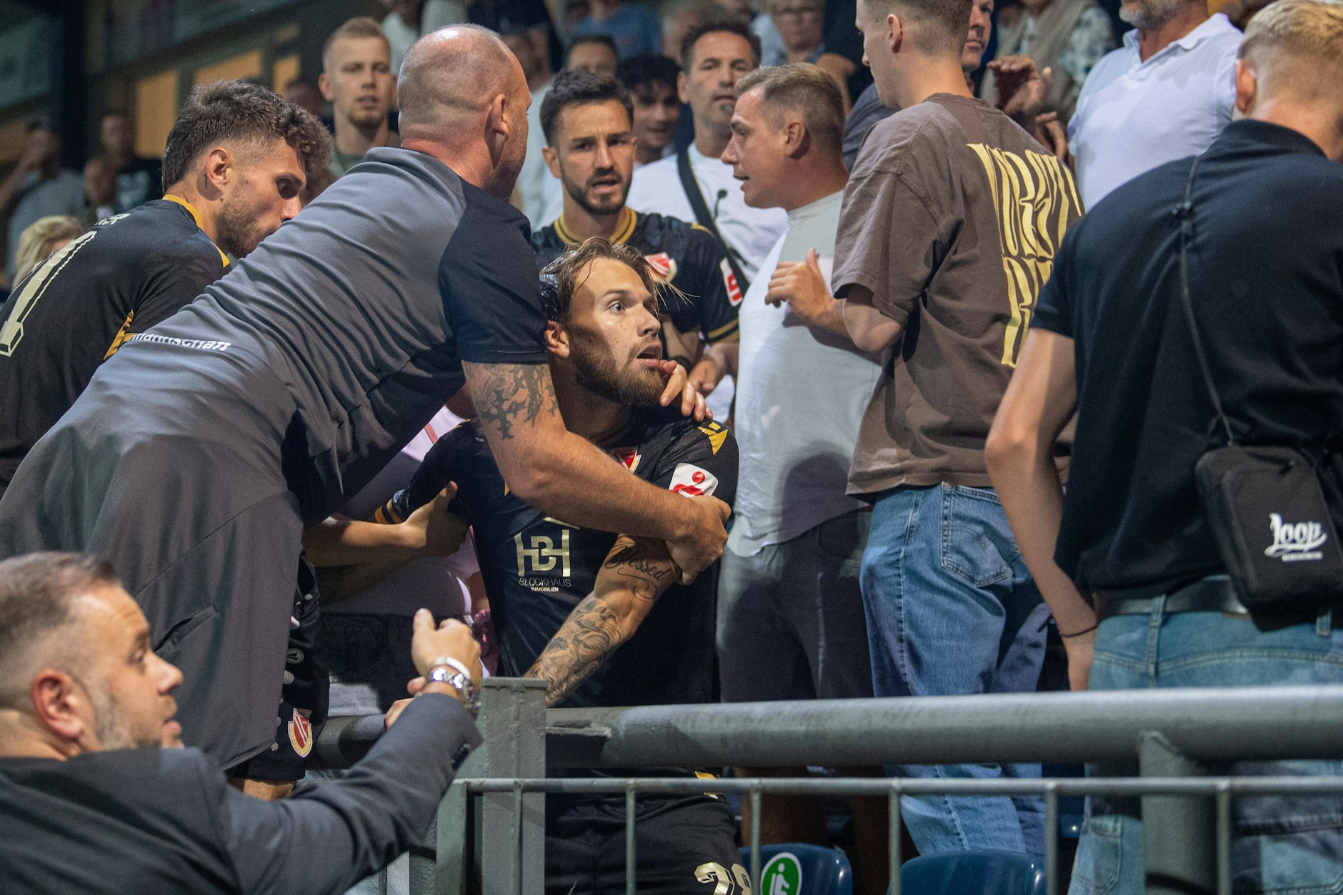Nach Abpfiff geraten Cottbuser Spieler und Verantwortliche mit Babelsberger Fans auf der Haupttribüne aneinander. Der Cottbuser Niko Bretschneider (Mitte) muss von Mitspielern und Familie zurückgehalten werden.