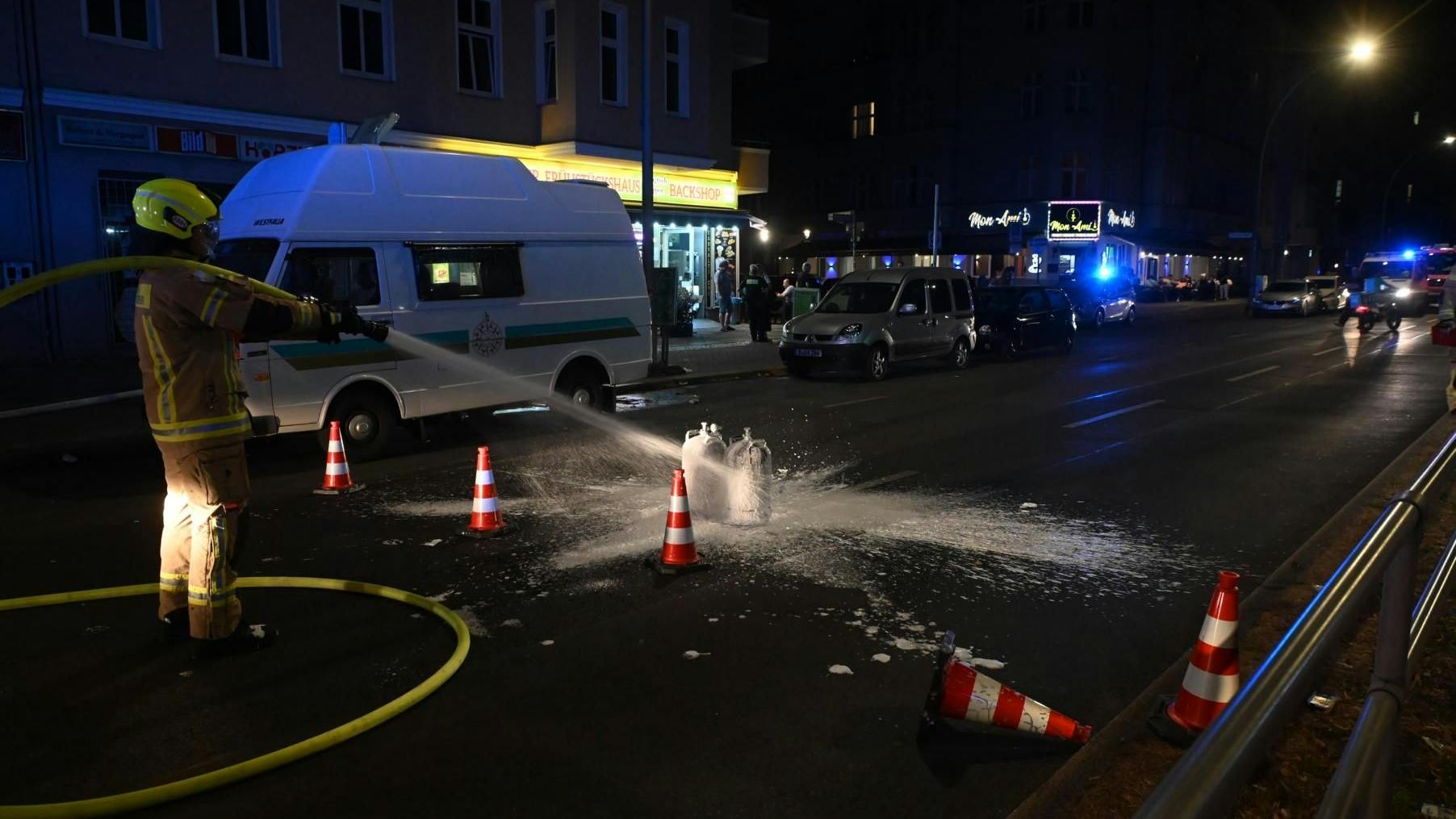 Ein Feuerwehrmann kühlt zwei Gasflaschen auf der Straße, um eine Explosion zu verhindern.
