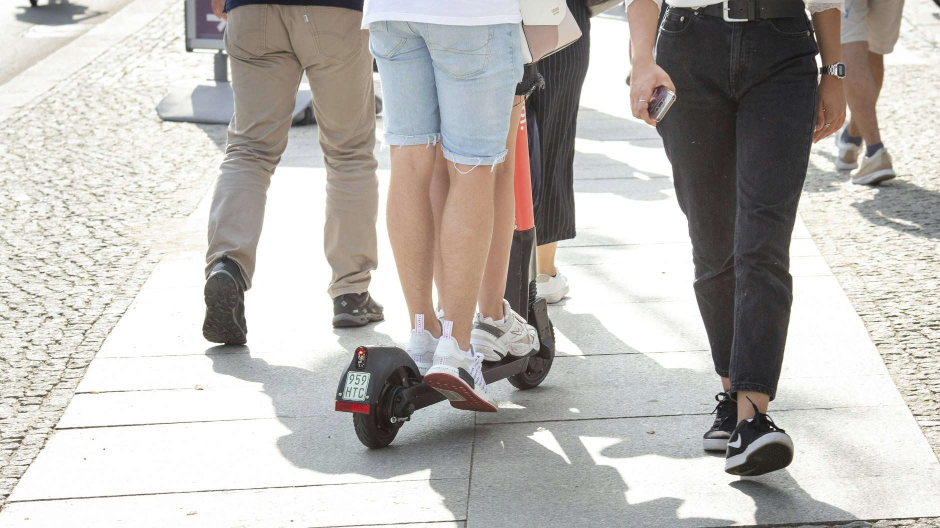Zwei Benutzer auf einem E-Scooter fahren in der Innenstadt von Berlin auf dem Fußweg