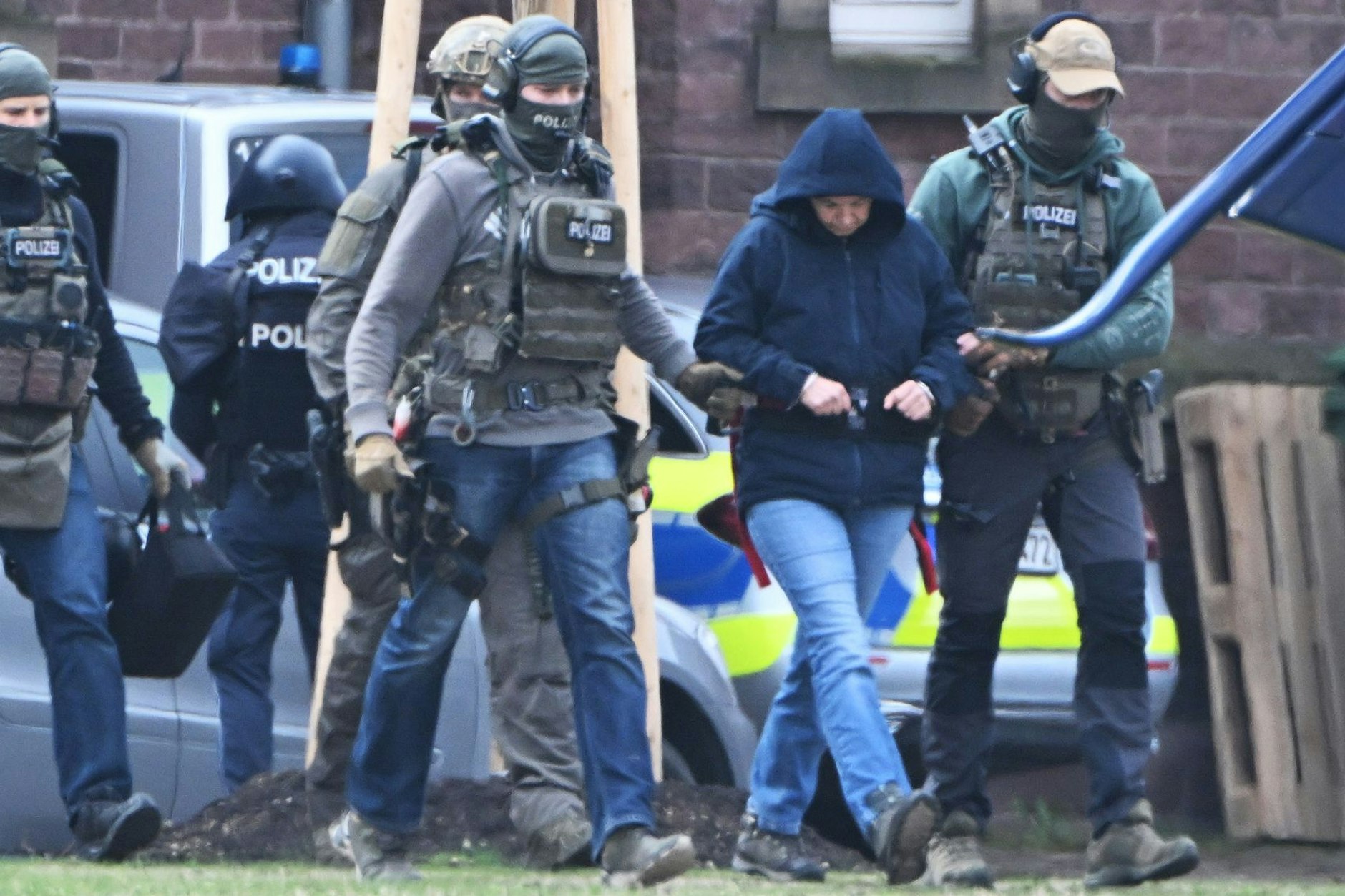 Die frühere RAF-Terroristin Daniela Klette wird von Polizeibeamten zu einem Hubschrauber geführt.