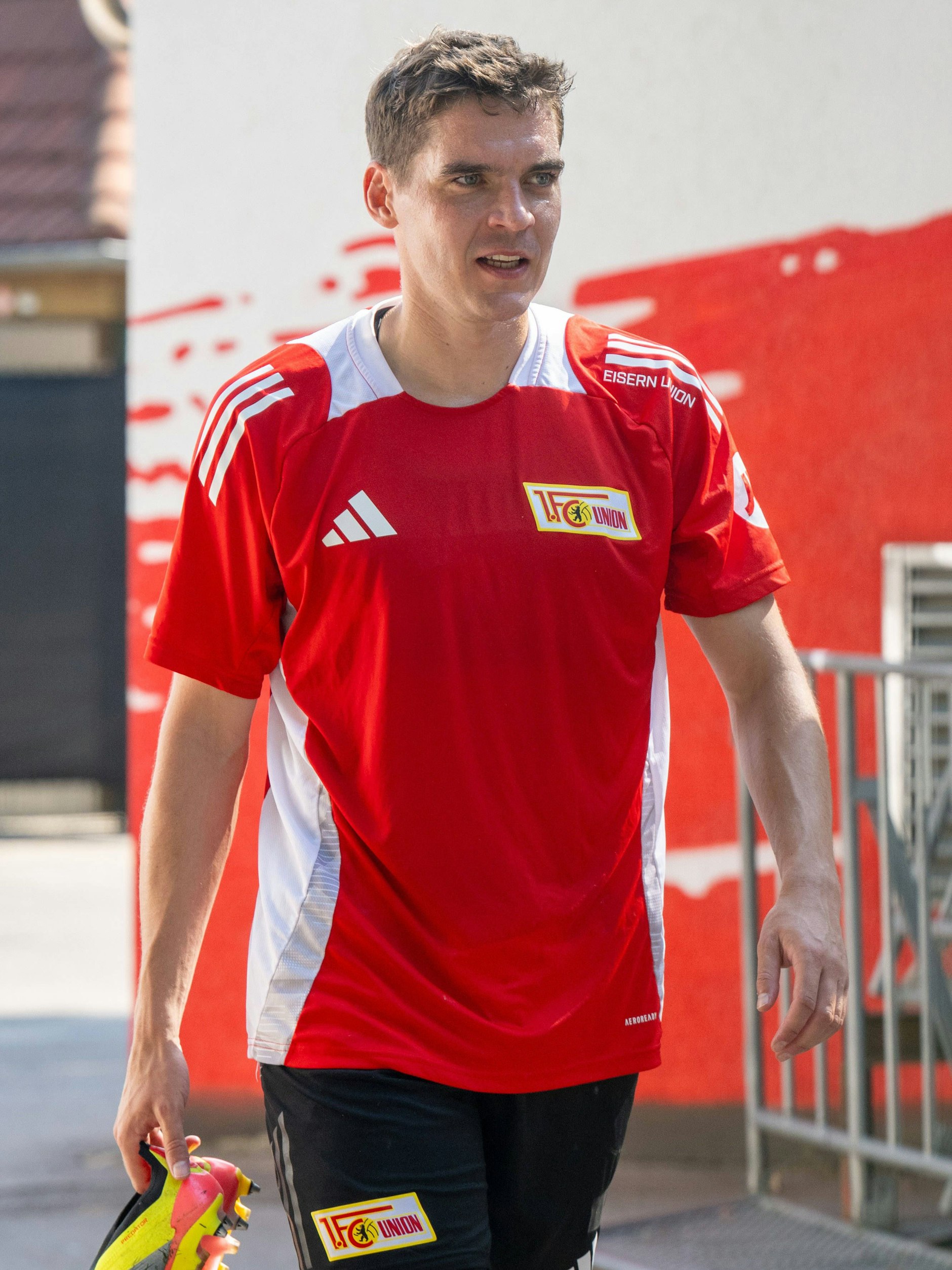 Robert Skov geht mit den Fußballschuhen in der Hand Richtung Kabine des 1. FC Union.