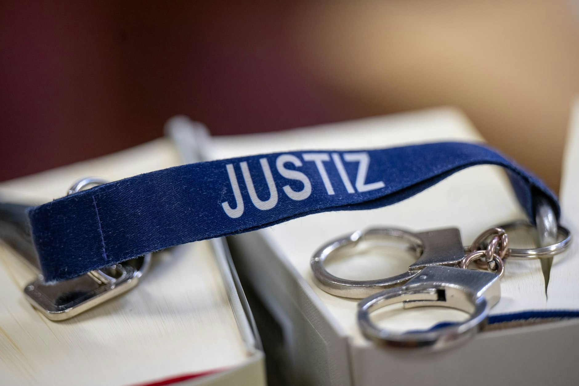 Ein Schlüsselanhänger mit dem Wort Justiz und Mini-Handschellen liegen auf zwei Gesetzbüchern im Büro einer Richterin im Kriminalgericht Berlin-Moabit.