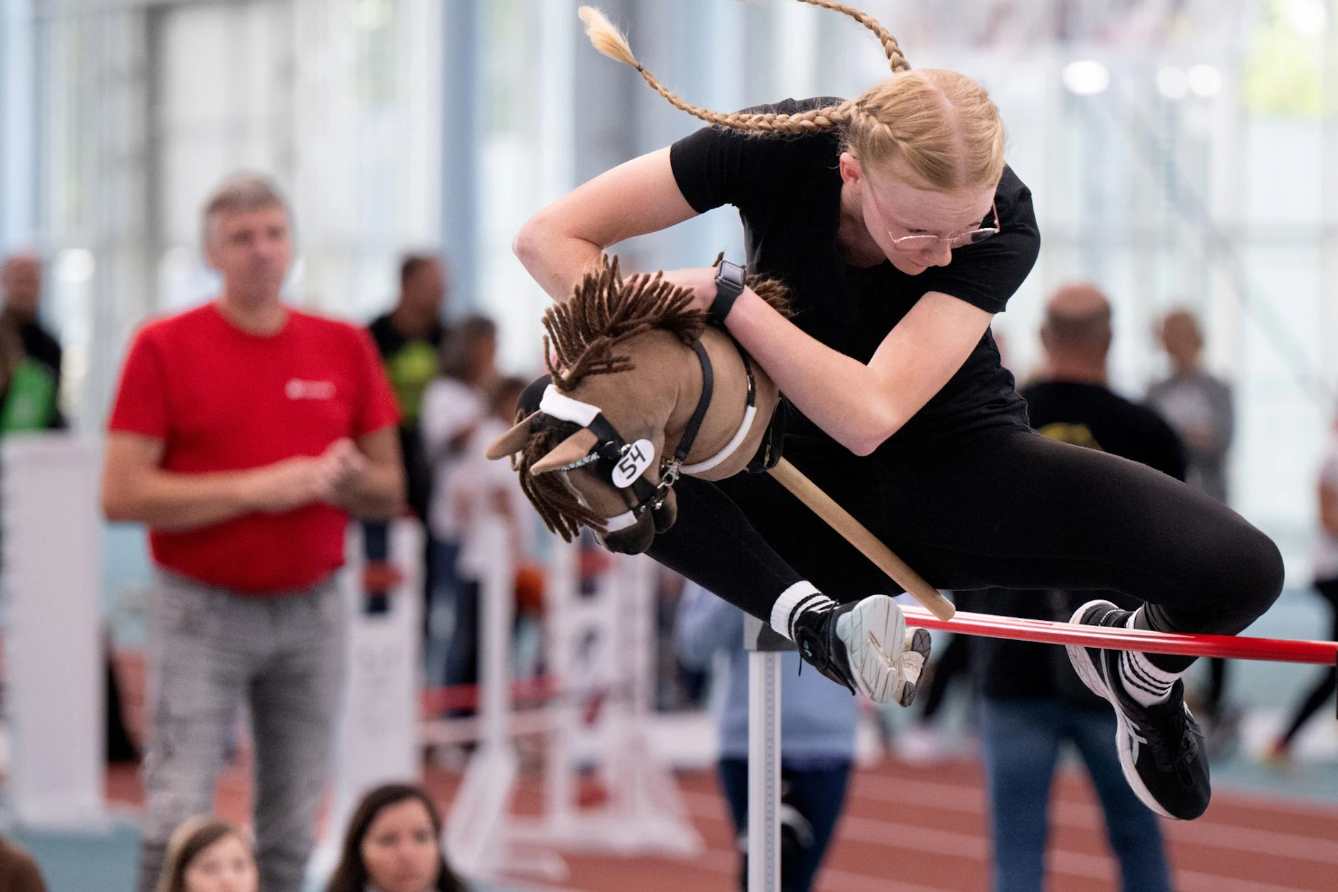 Teilnehmerin springt im Hobby-Horsing beim Hochsprung über das Hindernis.