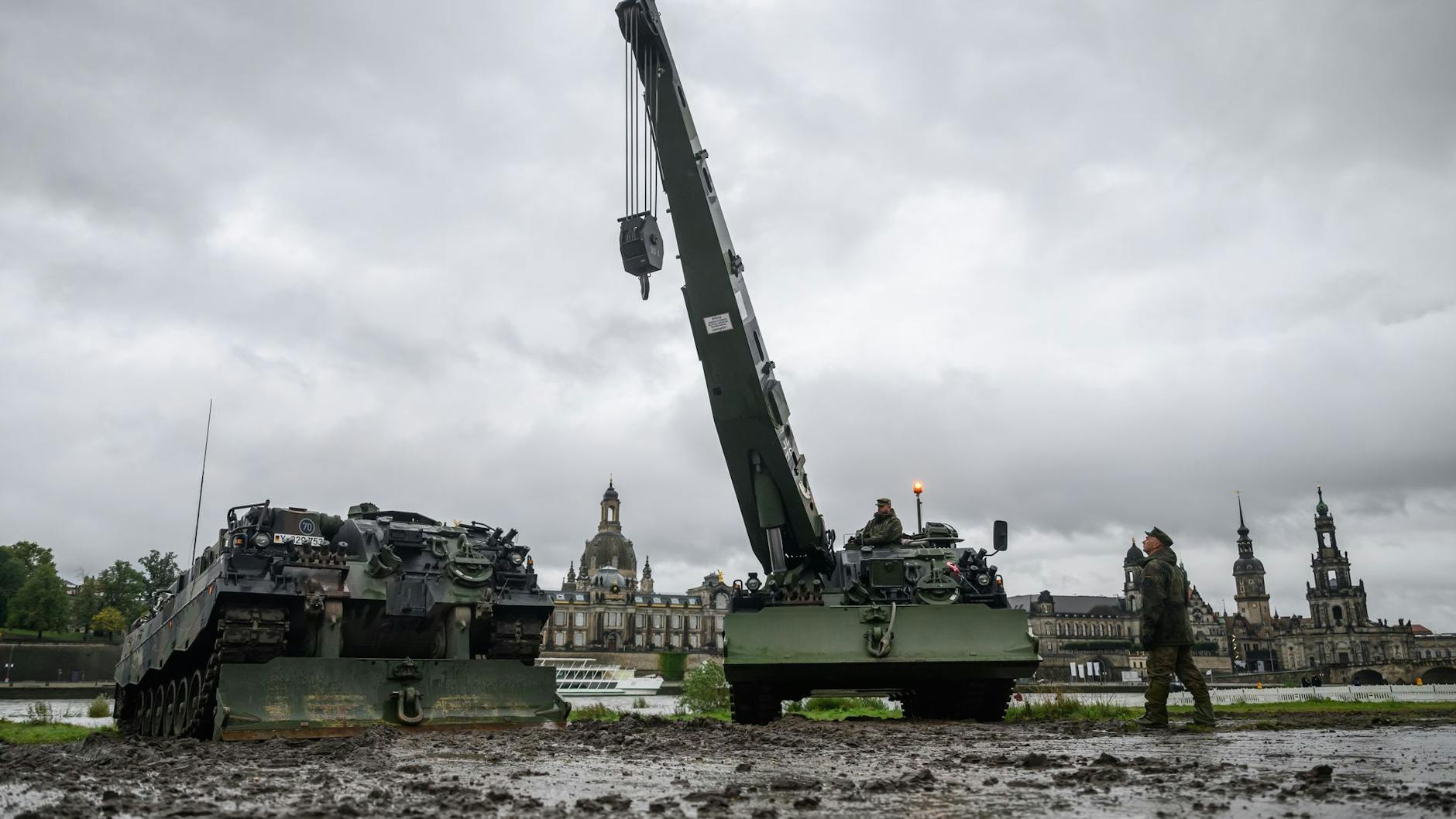 Zwei Bergepanzer 3 der Bundeswehr, auch „Büffel“ genannt, stehen vor der historischen Altstadtkulisse neben der eingestürzten Carolabrücke, um im Fall eines Hochwassers Baumaschinen zu bergen.