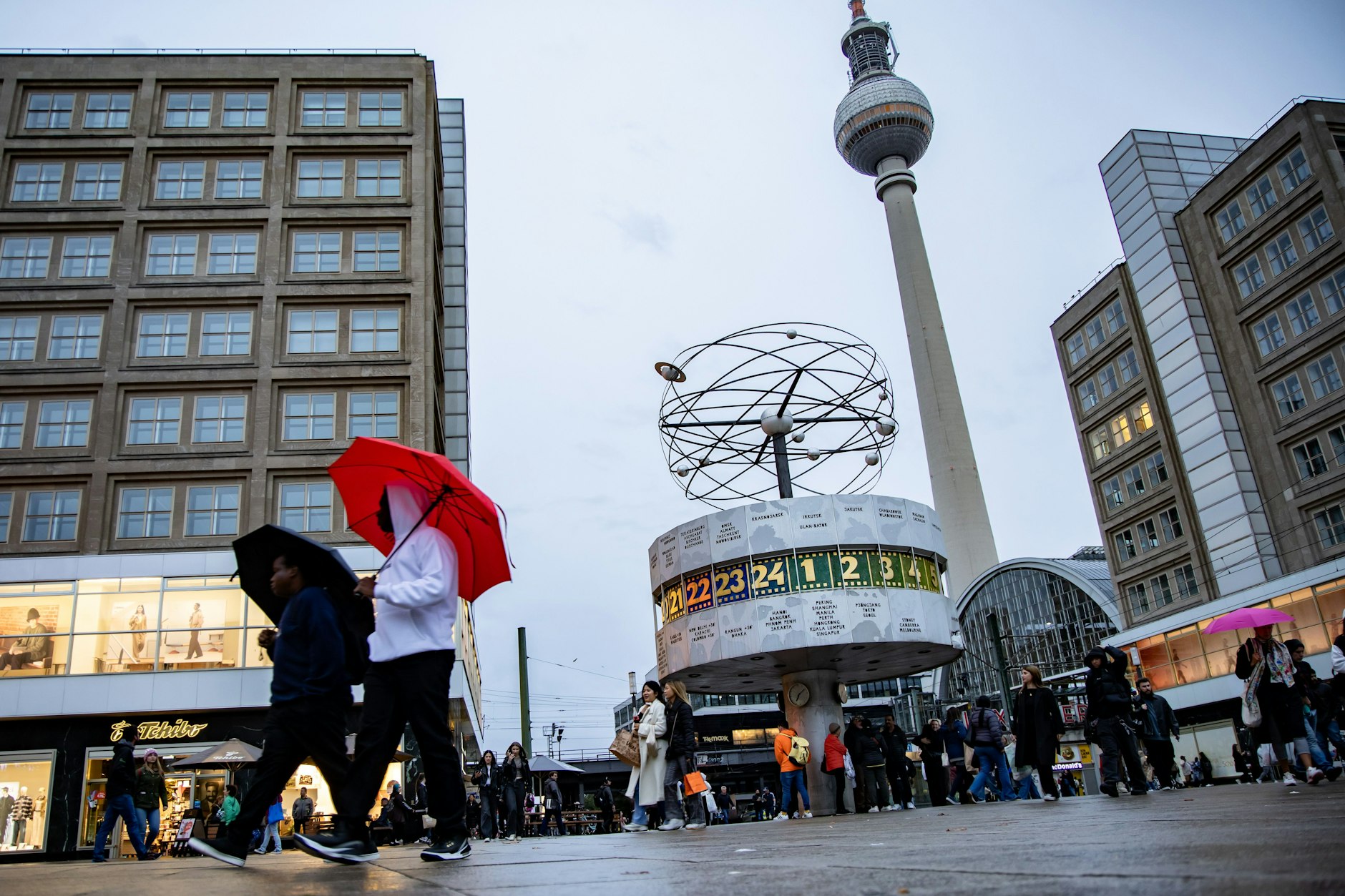Menschen laufen am Alexanderplatz an einem Regentag in Berlin.