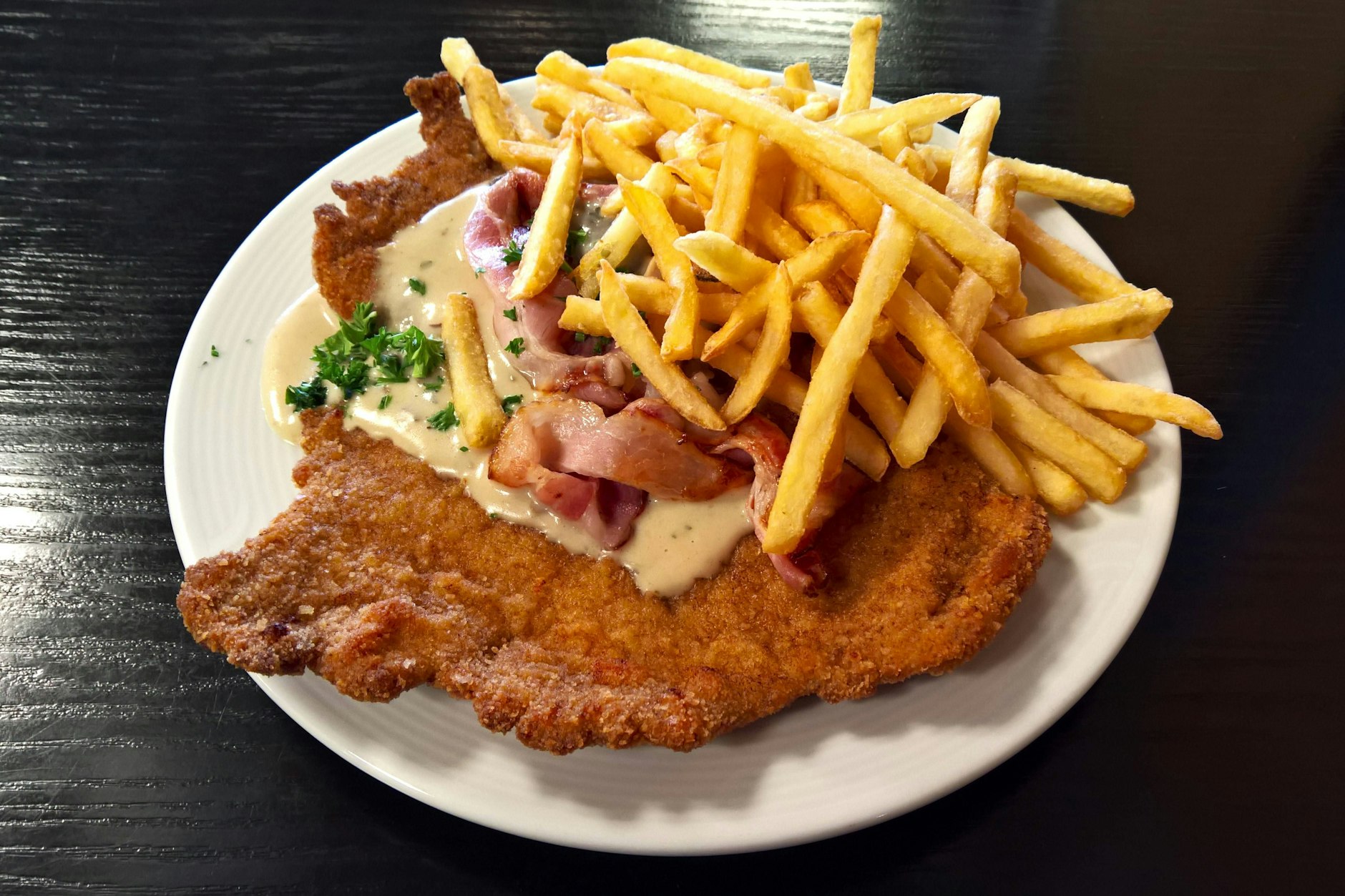 So kenne ich es, das panierte Jägerschnitzel mit Pommes. Das Jägerschnitzel ist ein Gericht der österreichischen Küche. Es ist eine Ableitung des Naturschnitzels, die normal ohne Panade serviert wird. Im deutschsprachigen Raum versteht man darunter auch oft ein paniertes Kalbs- oder Schweineschnitzel mit einer Pilzsauce. 