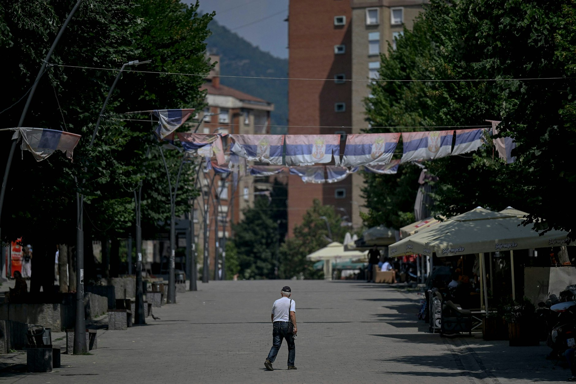 Am 16. August 2024 geht ein Kosovo-Serbe unter serbischen Nationalflaggen nahe der Mitrovica-Brücke, die seit dem Krieg 1999 Serben und Albaner in der Stadt trennt.