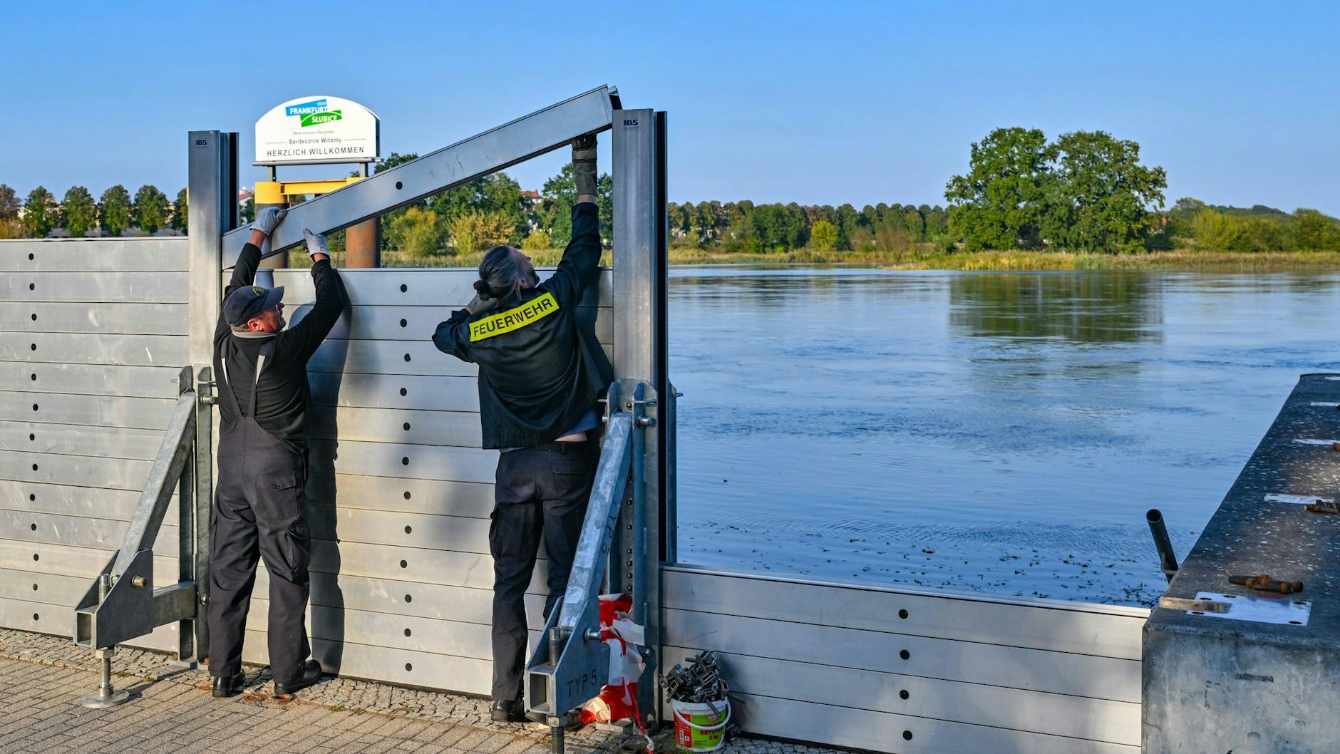 Zwei Kameraden der Freiwilligen Feuerwehr errichten eine mobile Hochwasserschutzwand am deutsch-polnischen Grenzflusses Oder.