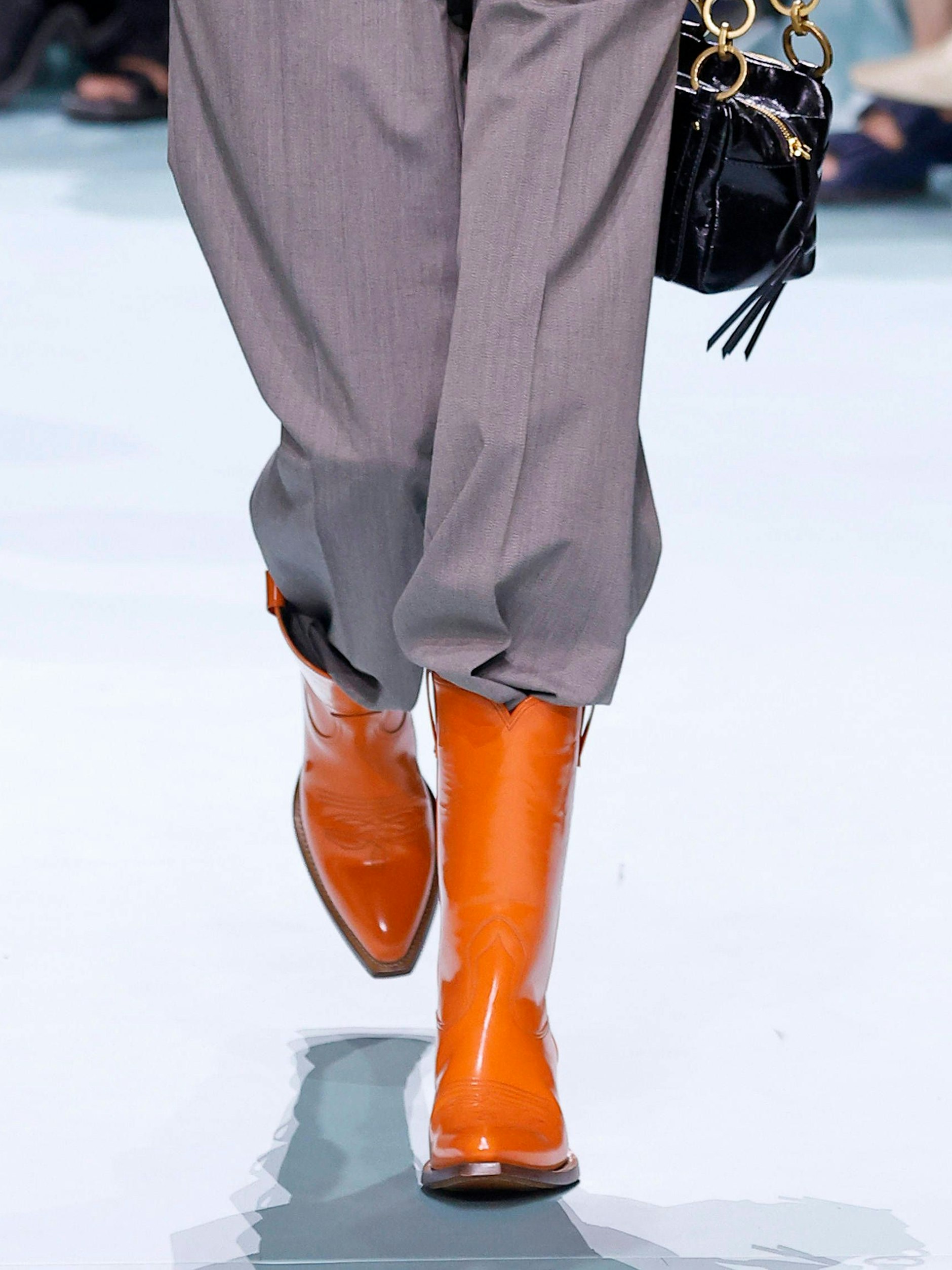 Cowboy-Boots waren in den vergangenen Prada-Kollektionen immer wieder in verschiedenen Varianten zu sehen. Im Sommer 2025 kommen sie in orangefarbenem Lackleder daher.