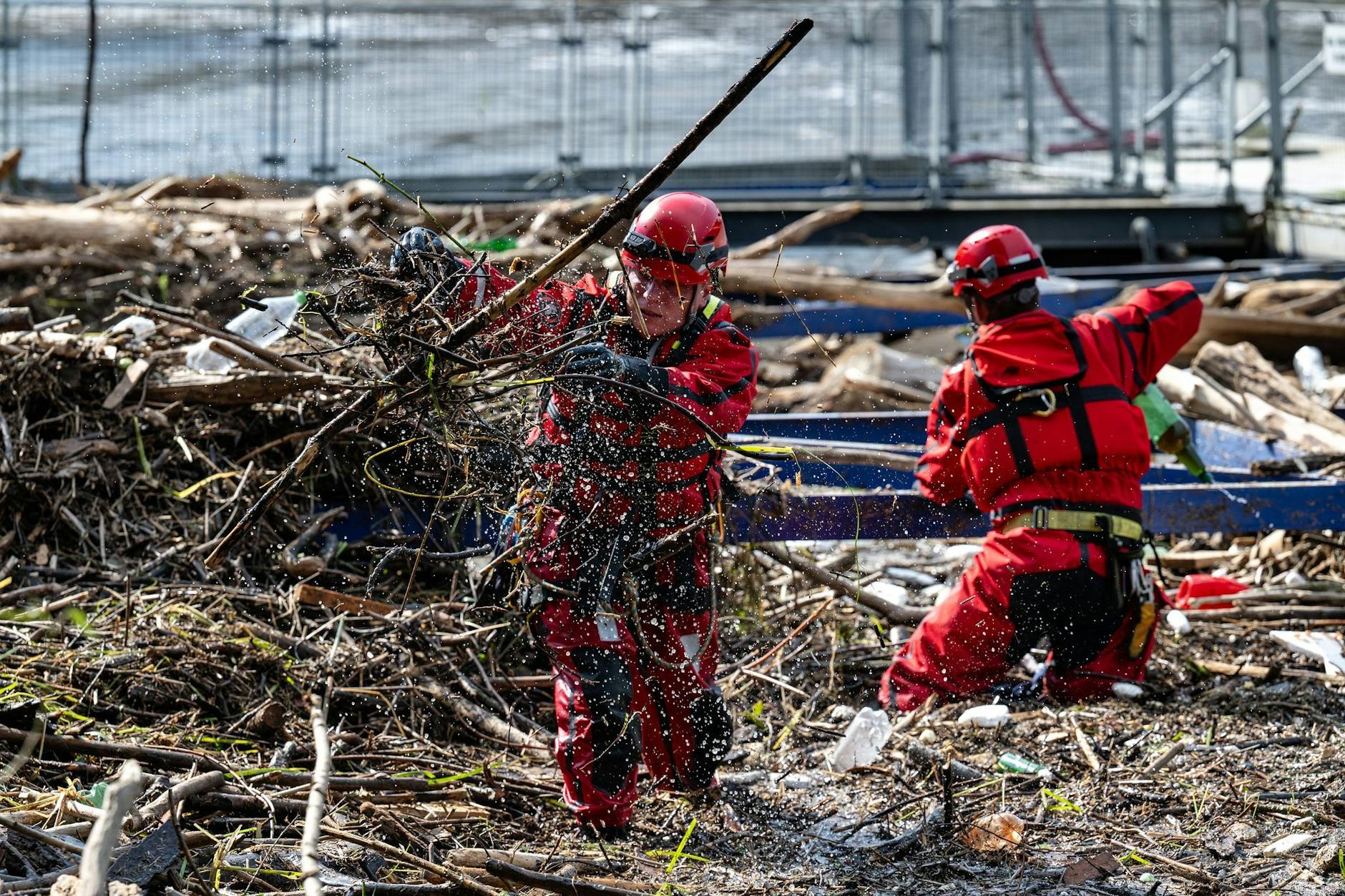 Zwei Personen entfernen nach dem Hochwasser Schlamm und Äste von der Anlegestelle vor der Wonka-Brücke.
