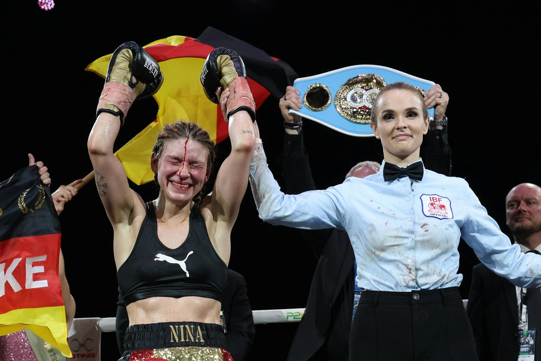 Die Berlinerin Nina Meinke jubelt in Hamburg nach der Urteilsverkündung, hinter ihr die Deutschlandfahne und ihr WM-Gürtel.