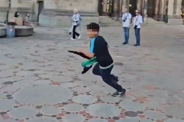 Ein Junge mit Palästina-Flagge flüchtet vor Polizeibeamten.