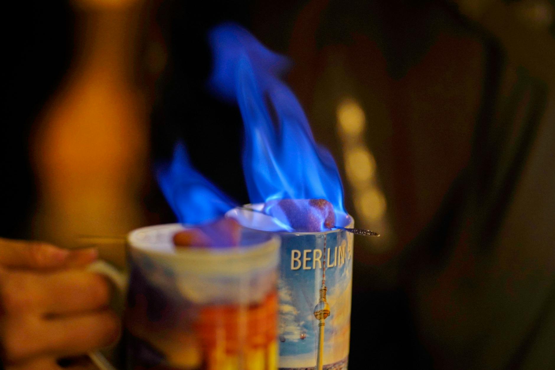Anstoßen mit Feuerzangenbowle im Berlin-Pott mit blauer Flamme: Atmosphäre an einem Berliner Weihnachtsmarkt.