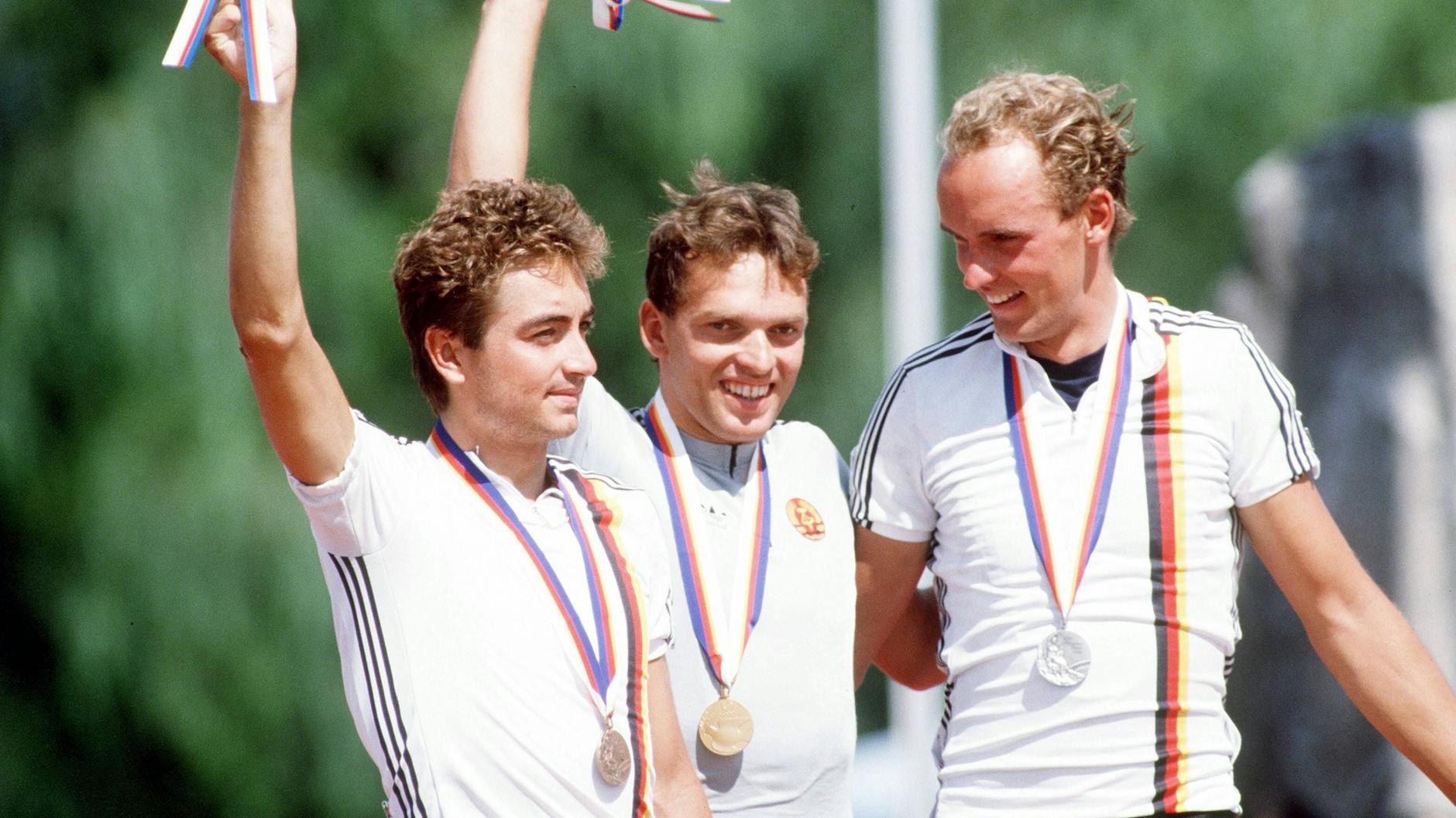 Im Straßenrennen bei Olympia 1988 feiern Christian Henn, Olaf Ludwig (beide DDR) und Bernd Gröne (BRD) das deutsche Podium bei der Siegerehrung.