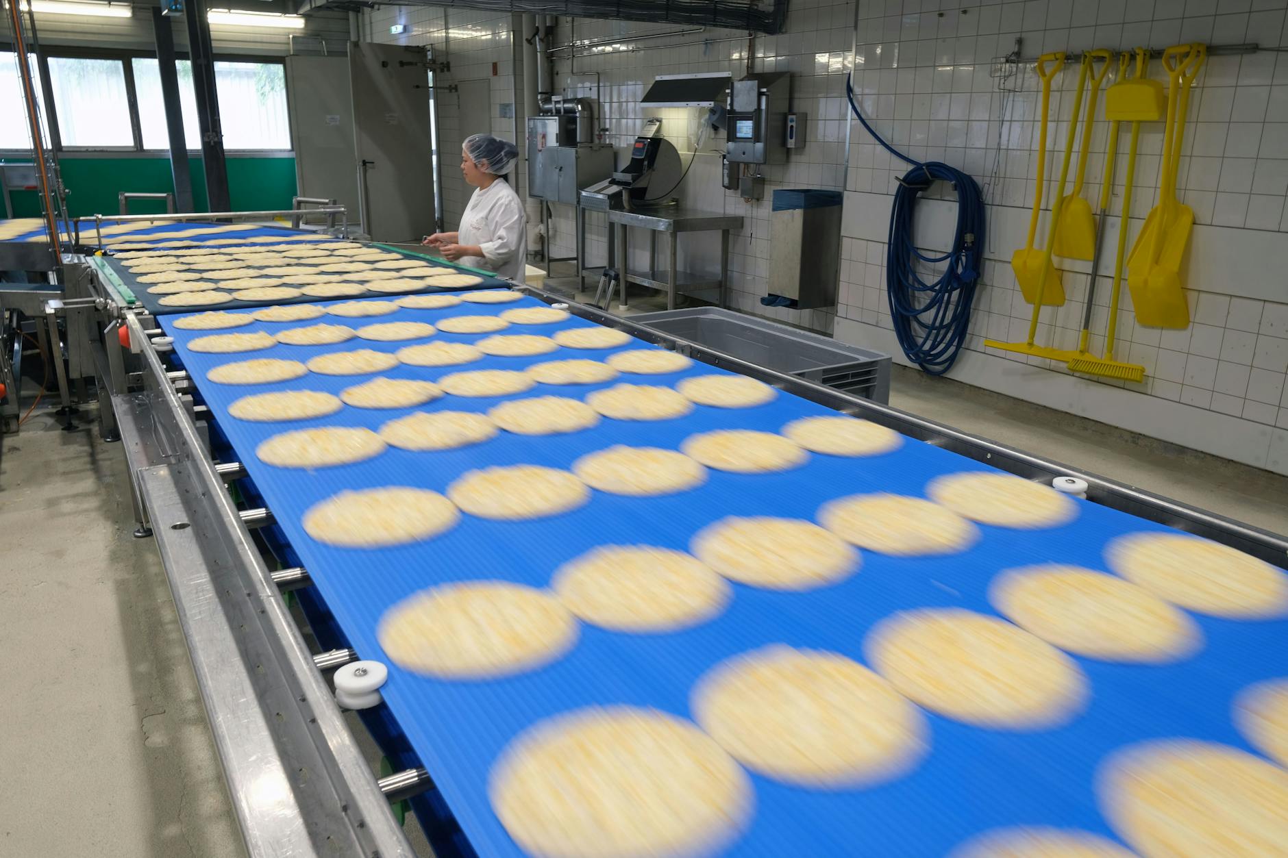 Mitarbeiterin Vyngo Le kontrolliert die belegten Pizzen, bevor sie verpackt werden.