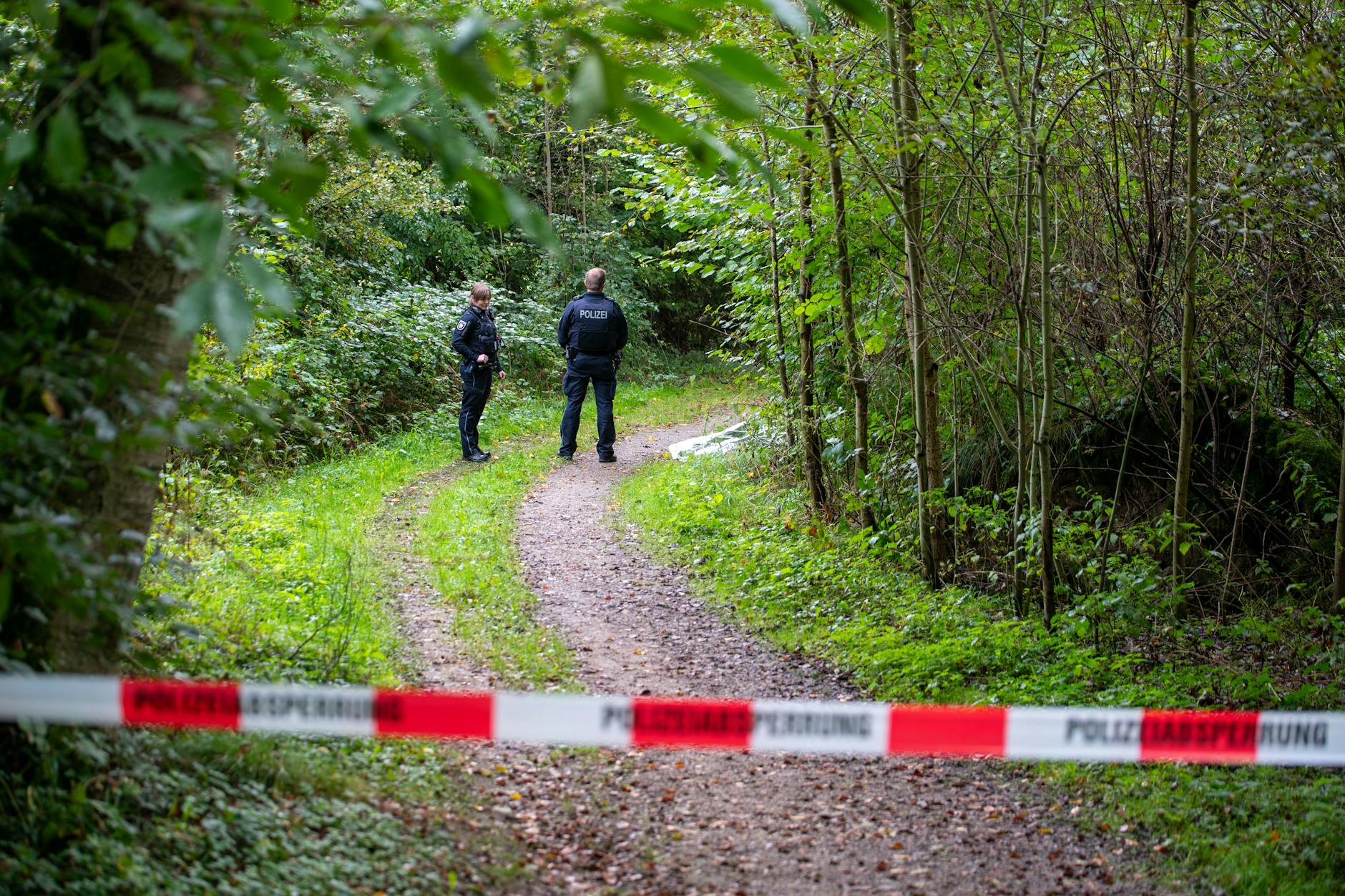 Witzeeze in Schleswig-Holstein: Polizisten stehen auf einem abgesperrten Waldweg. Dort wurde die Leiche gefunden.