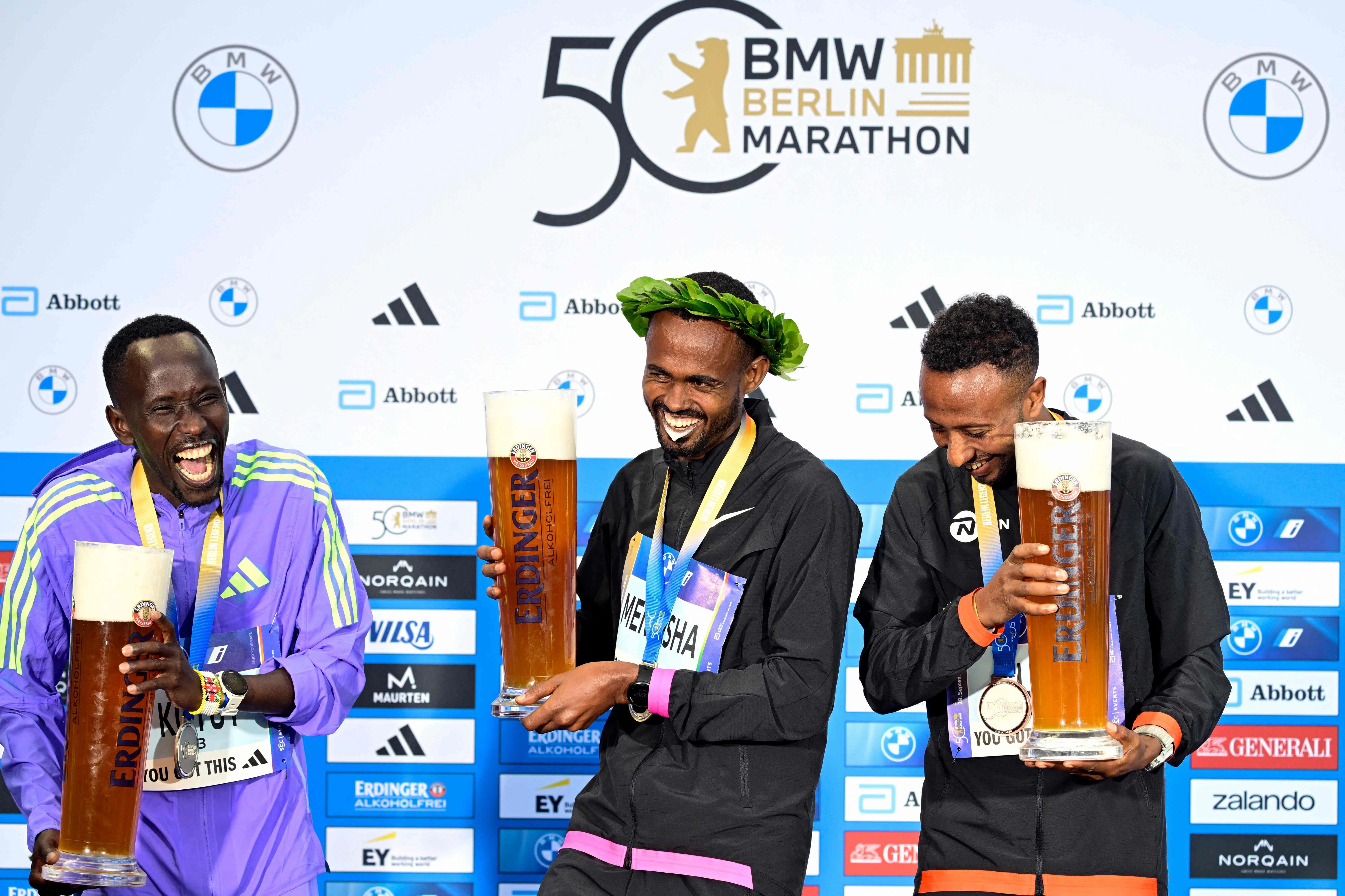 Der äthiopische Sieger Milkesa Mengesha (Mitte) feiert auf dem Podium mit dem zweitplatzierten Kenianer Cybrian Kotut (links) und dem drittplatzierten Äthiopier Haymanot Alew (rechts) nach der 50. Auflage des Berlin-Marathons.