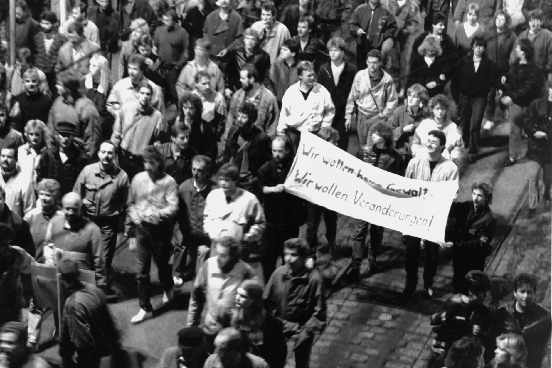 Montagsdemo am 9. Oktober 1989 in Leipzig. Ein Transparent mit der Aufschrift „Wir wollen keine Gewalt! Wir wollen Veränderungen!“ wird hochgehalten.