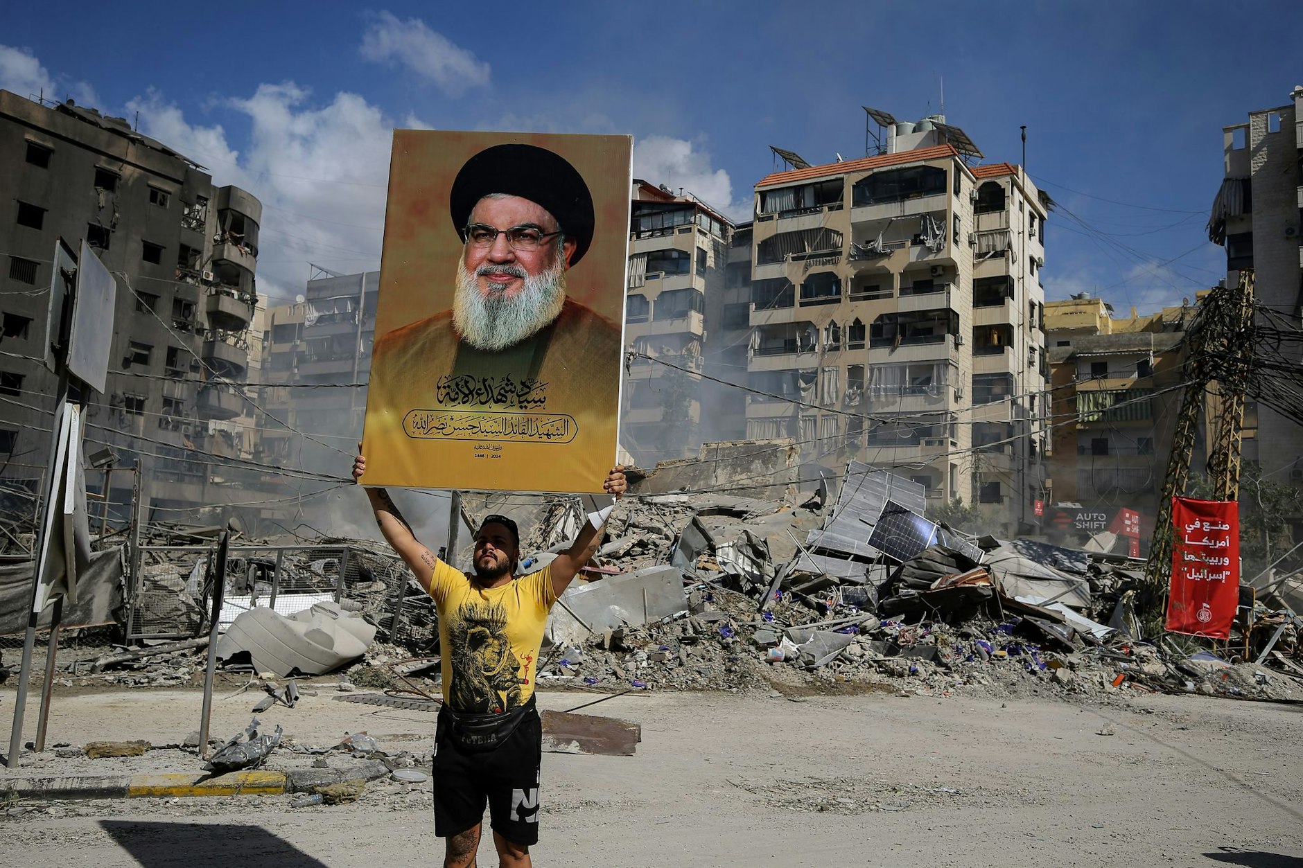 Ein Hisbollah-Anhänger hält ein Poster des getöteten Hassan Nasrallah vor einem Gebäude hoch, das bei einem israelischen Luftangriff auf einen südlichen Vorort von Beirut zerstört wurde.