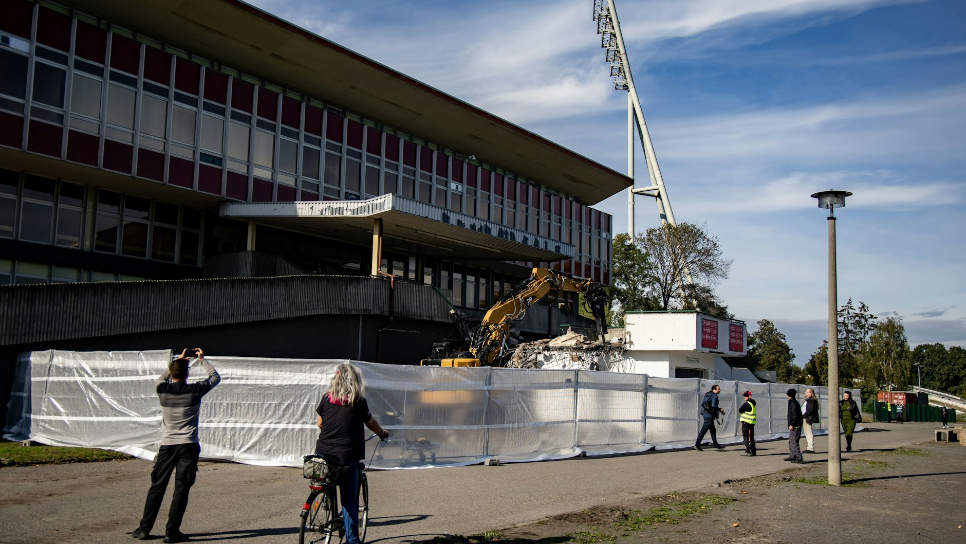 Anwohner und Sportpark-Besucher sehen dem Abriss zu.