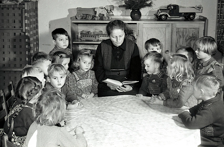Eine Erzieherin in der Kinderkrippe Köpenick liest Kindern aus einem Buch vor.