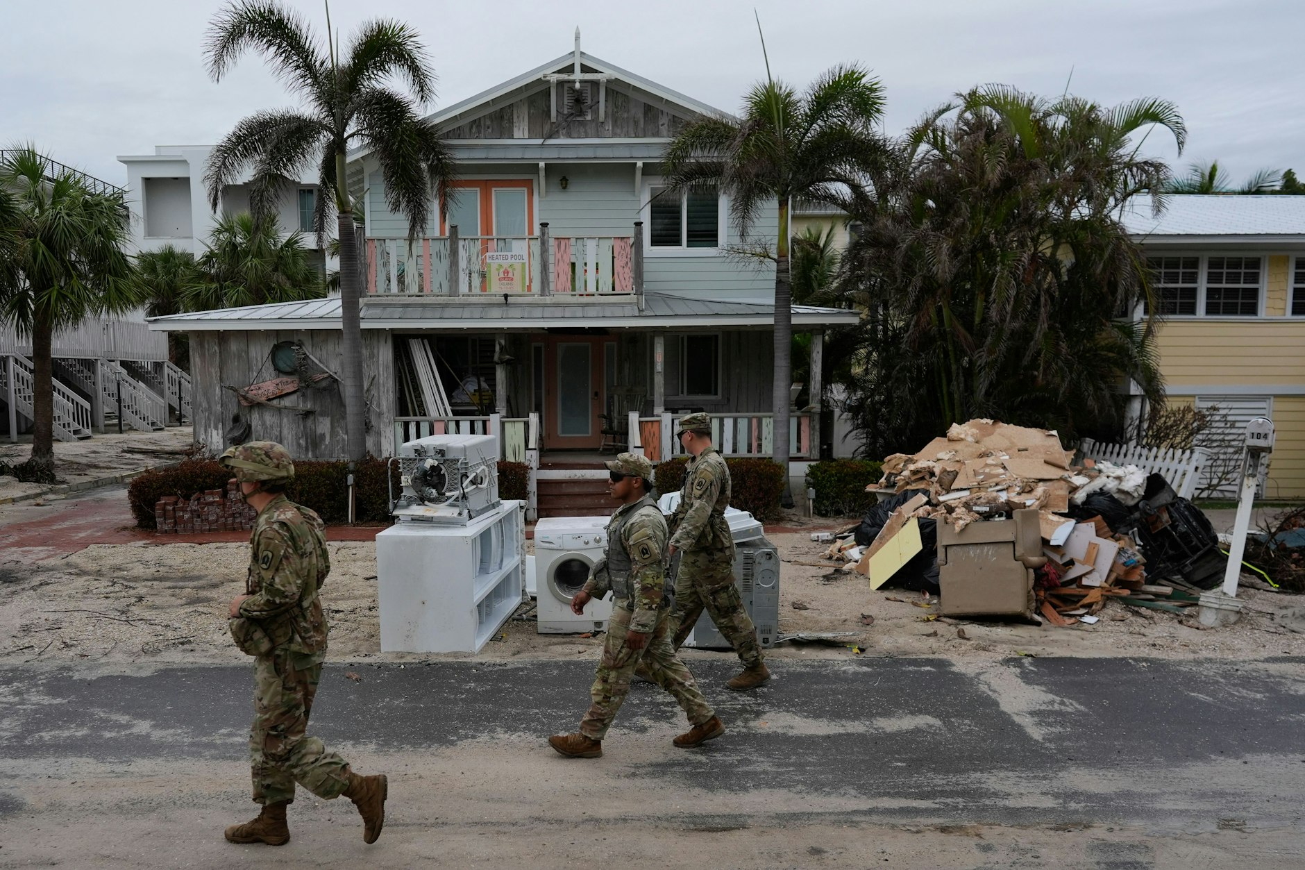 Angehörige der Nationalgarde der Armee Floridas suchen nach verbliebenen Bewohnern im fast menschenleeren Bradenton Beach, bevor der Hurrikan „Milton“ auf Anna Maria Island eintrifft.. Vor den beschädigten Häusern liegen noch immer Schuttberge von den Überschwemmungen des Hurrikans „Helene“.