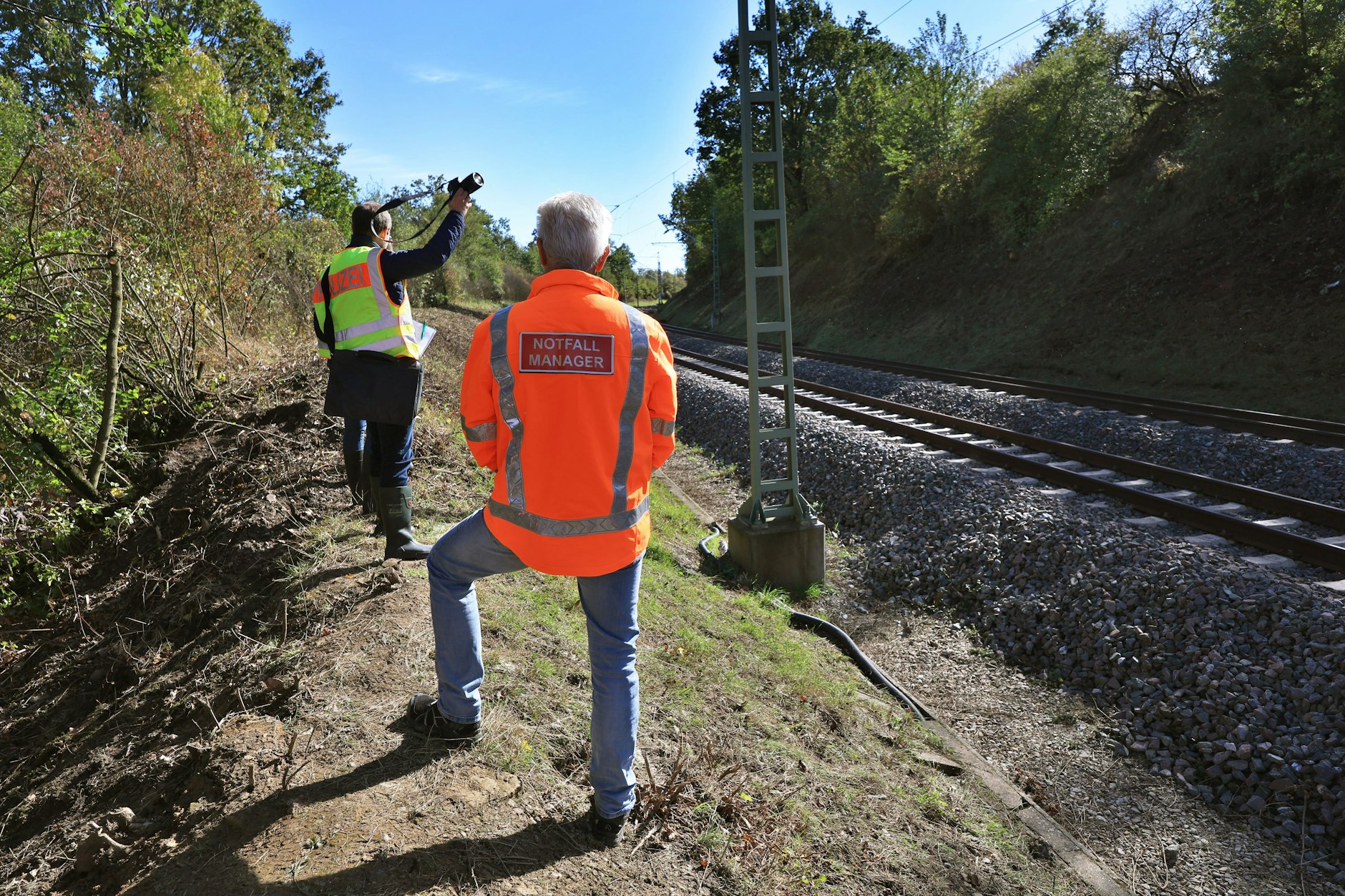 Ein Notfallmanager der Deutschen Bahn und Beamte der Kriminalpolizei untersuchen die Unfallstelle.  