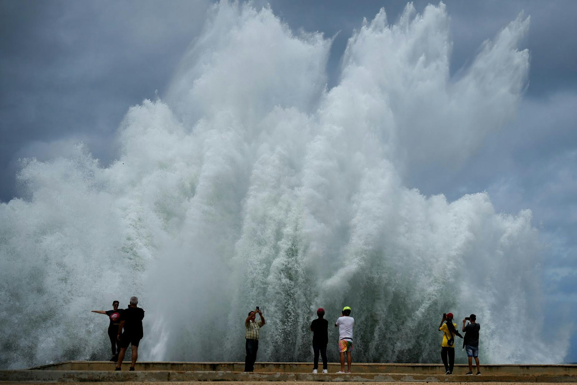 Menschen fotografieren die Gischt der Wellen, die vom Ende des Hurrikans „Milton“ gegen die Ufermauer des Malecon schlagen.
