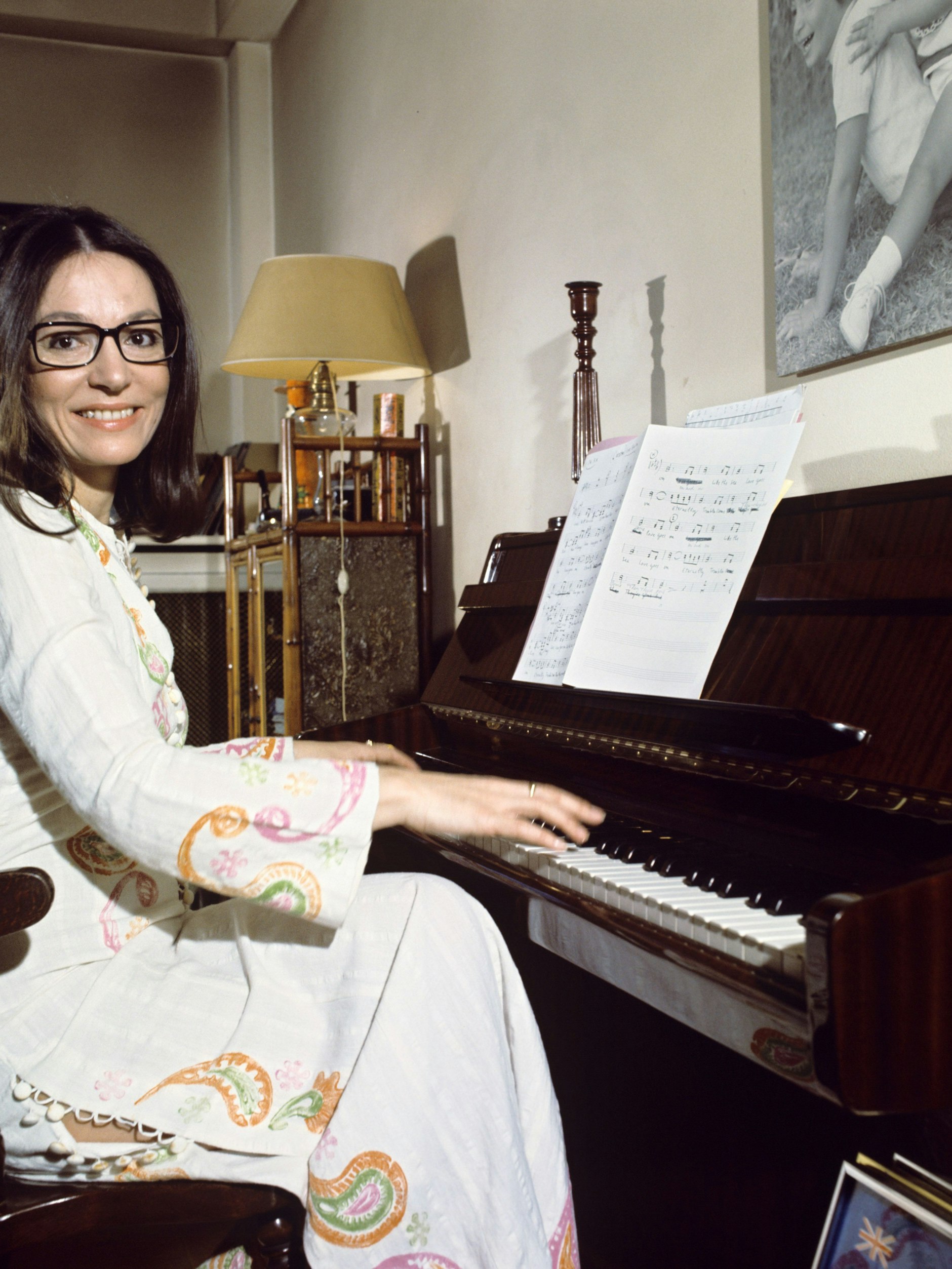 Die griechische Sängerin Nana Mouskouri sitzt an einem Klavier. Seit Jahrzehnten ist sie für viele Menschen die Stimme Griechenlands. Ihr Markenzeichen ist eine schwarze Brille.