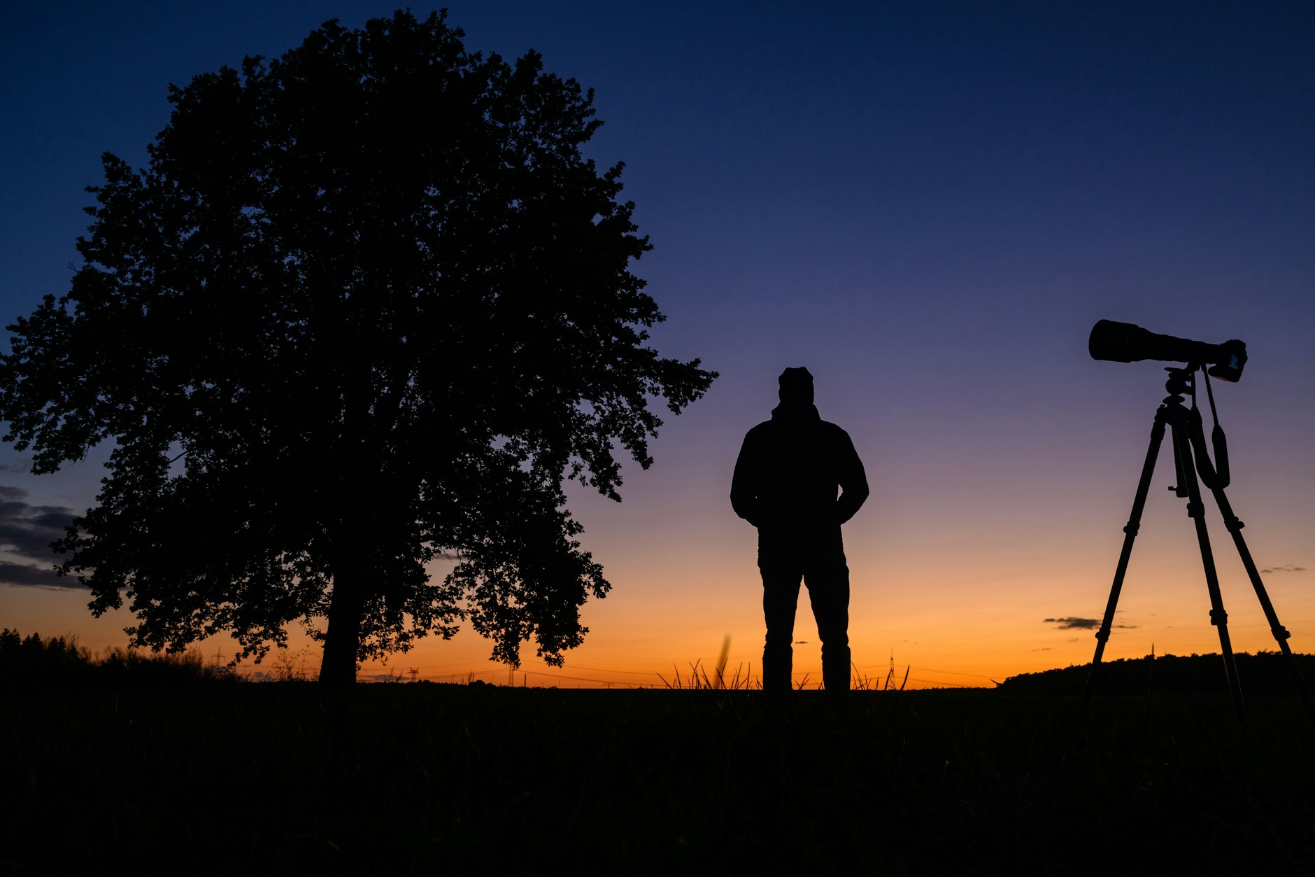 Brandenburg, Petersdorf: Ein Fotograf steht nach dem Sonnenuntergang mit seiner Ausrüstung auf einem Feld und wartet auf den Kometen Tsuchinshan-Atlas.