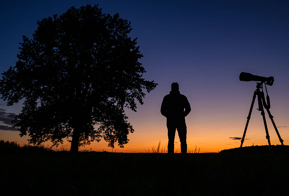 Brandenburg, Petersdorf: Ein Fotograf steht nach dem Sonnenuntergang mit seiner Ausrüstung auf einem Feld und wartet auf den Kometen Tsuchinshan-Atlas.