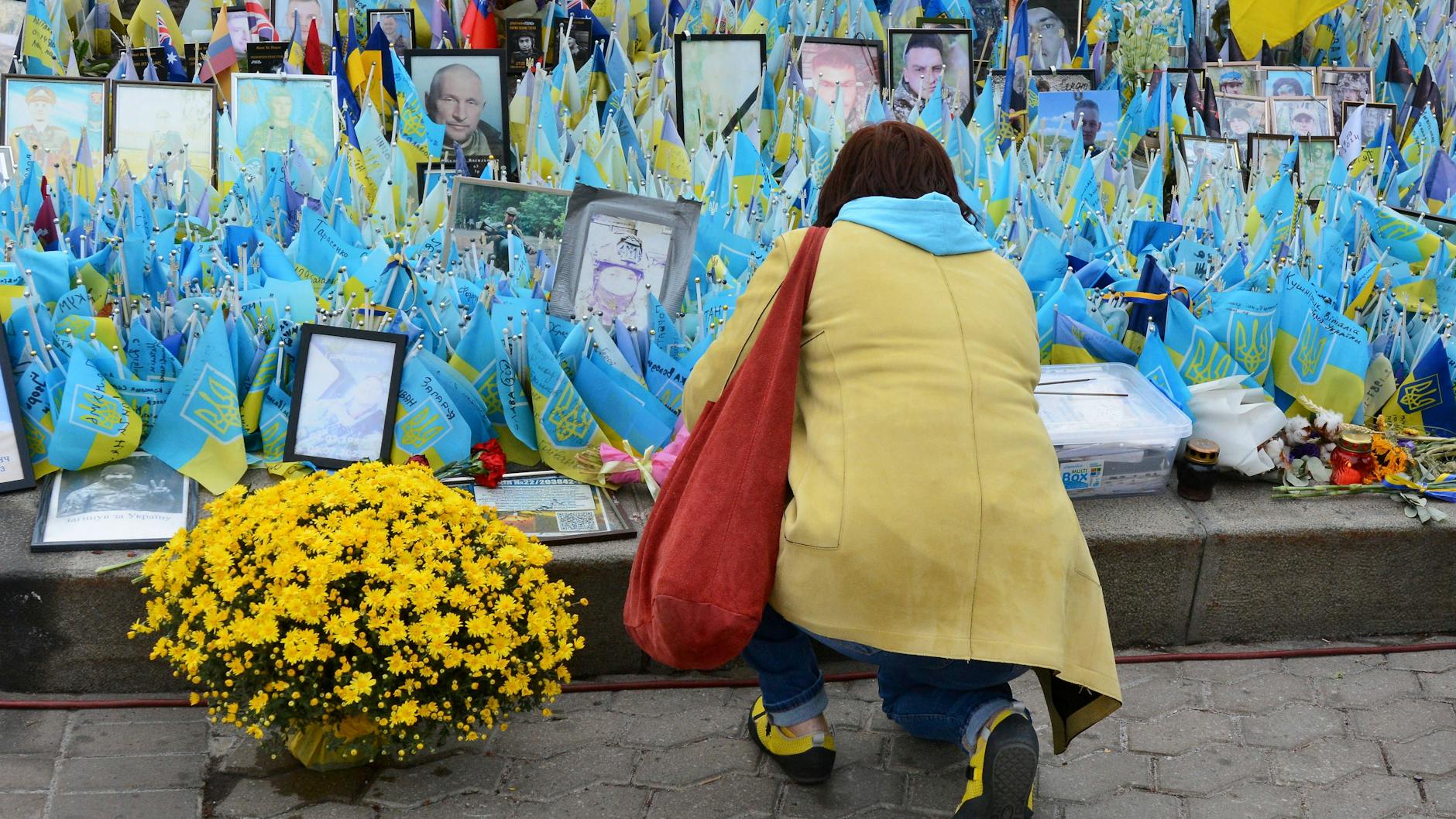 Eine Frau legt Blumen an einer Gedenkstätte für gefallene ukrainische Soldaten in Kiew nieder.