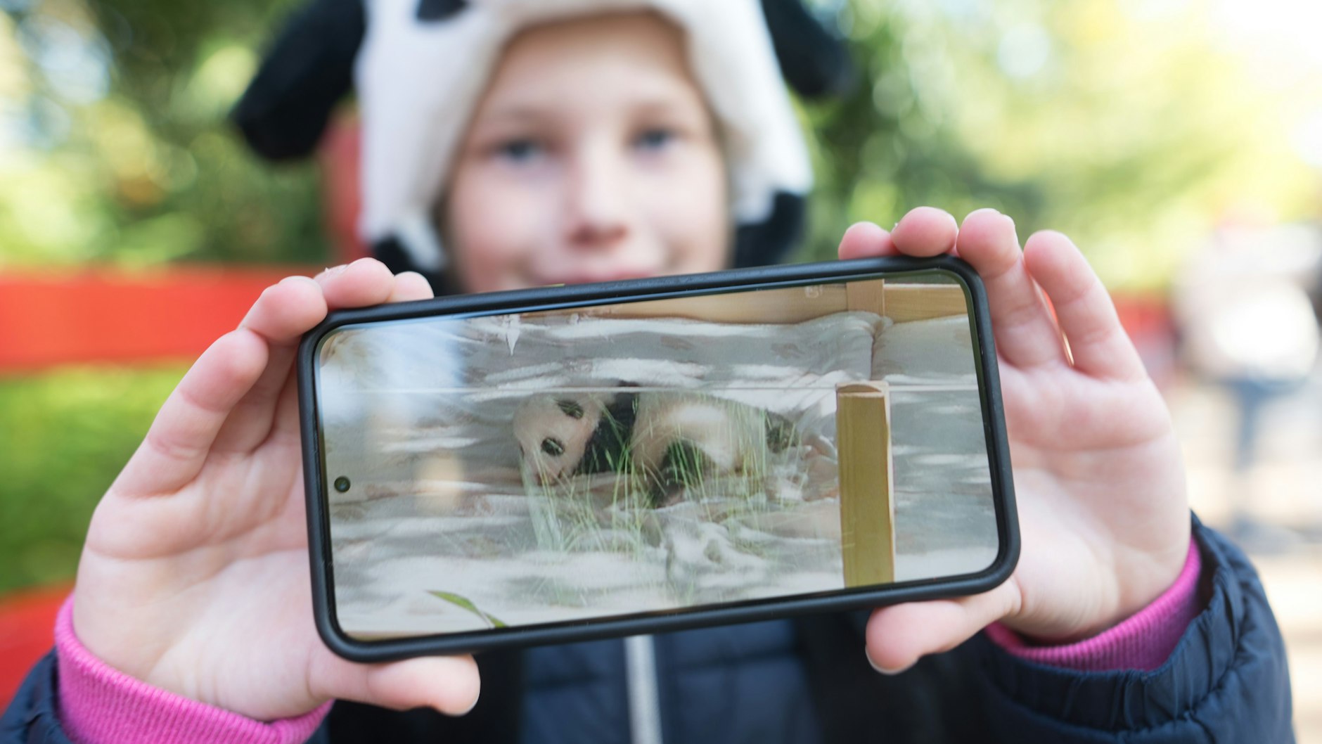 Auch Schülerin Bea hat sich im Berliner Zoo in die Warteschlange eingereiht. Ganz stolz zeigt sie das Handy-Foto, das sie von dem Panda-Baby gemacht hat.